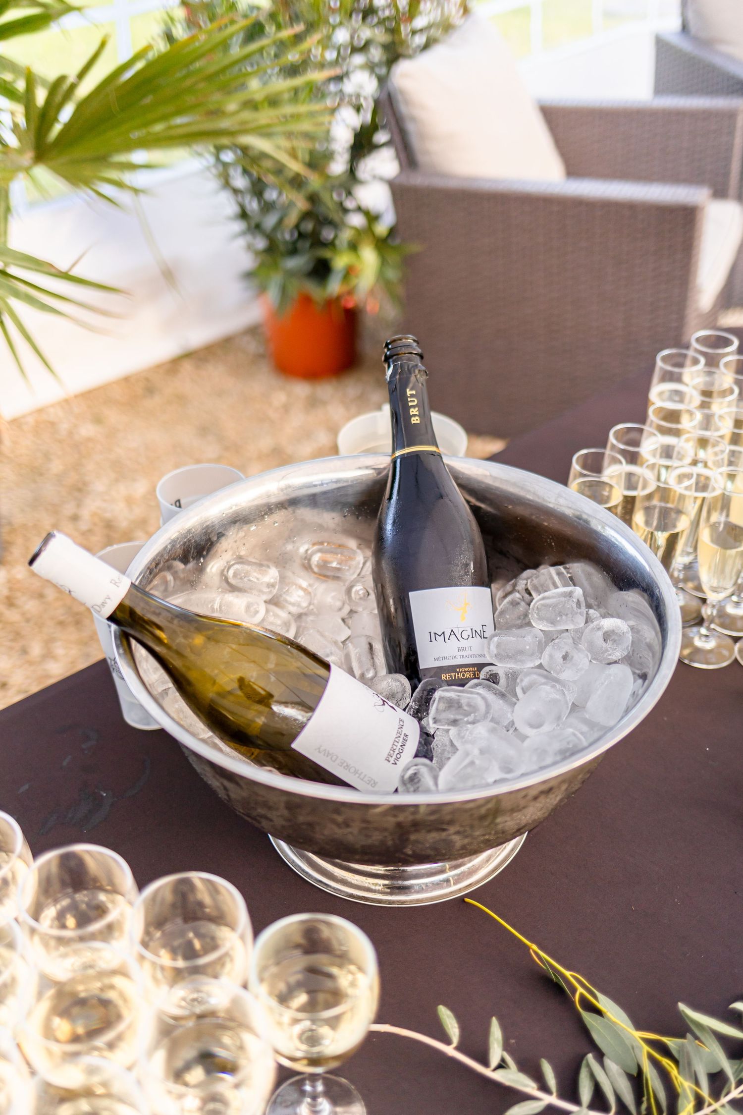 Champagne bottles chilling in silver ice bucket with empty glasses.
