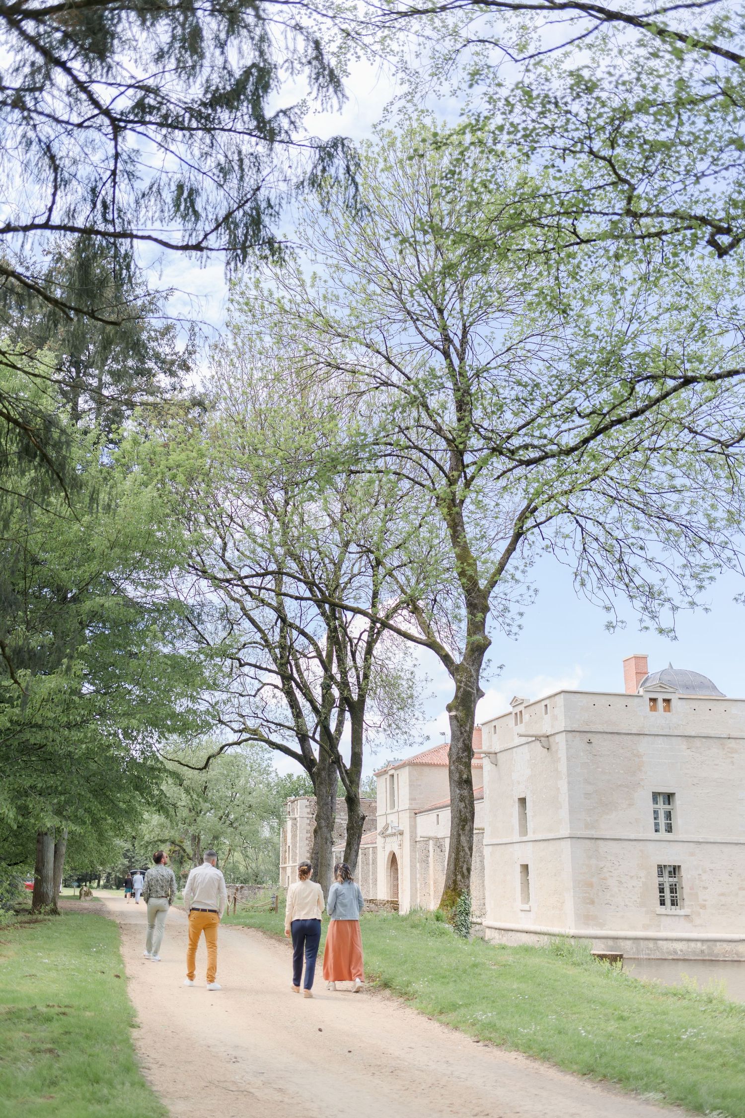 Scenic pathway leads to a historic stone castle through spring trees.
