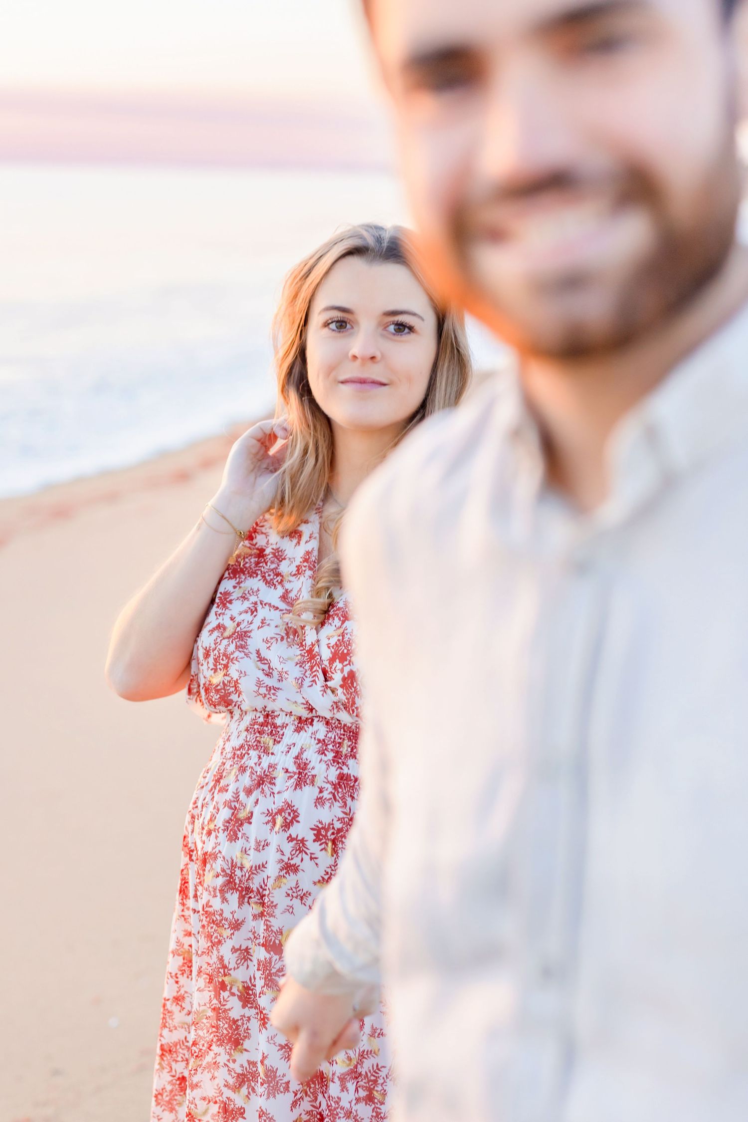 Candid moments between couple on beach during golden hour photography session.