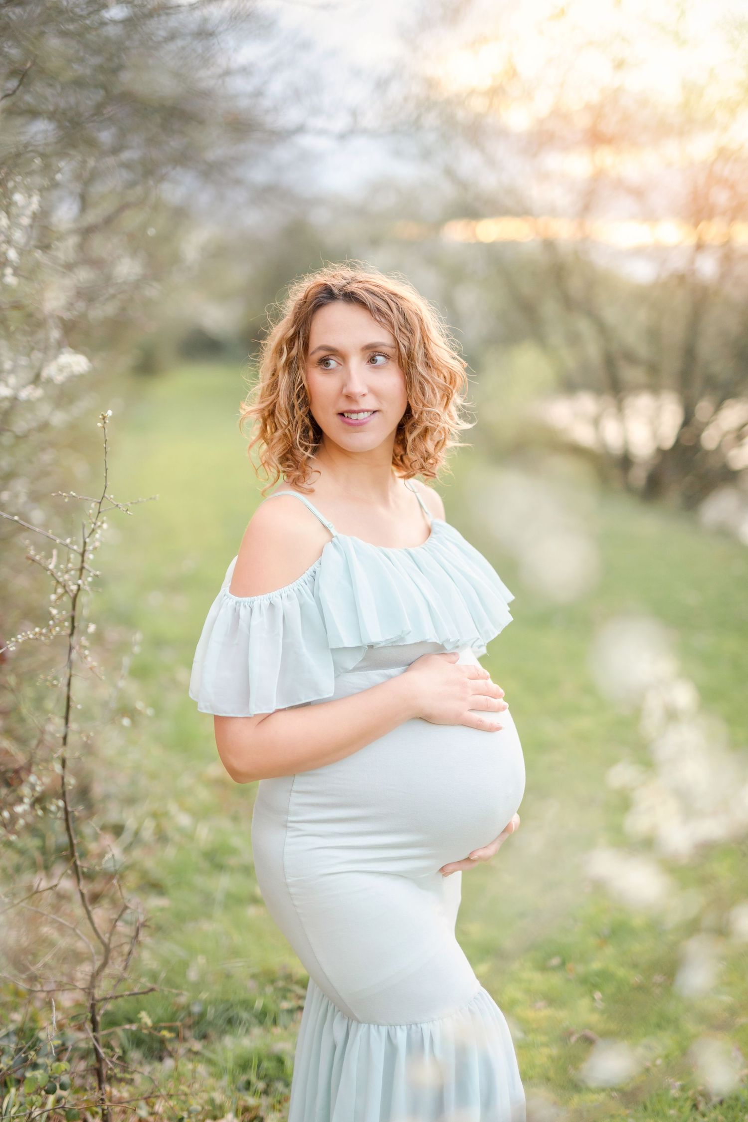 Beautiful spring maternity session with blossoming trees and golden sunlight.