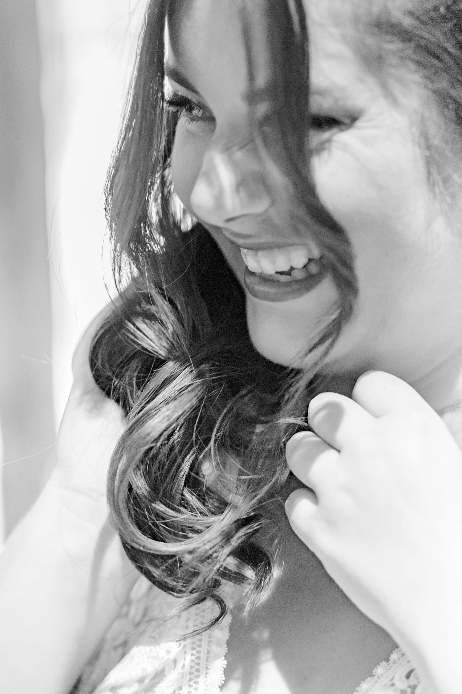 Black and white portrait capturing a joyful candid moment during wedding preparations.