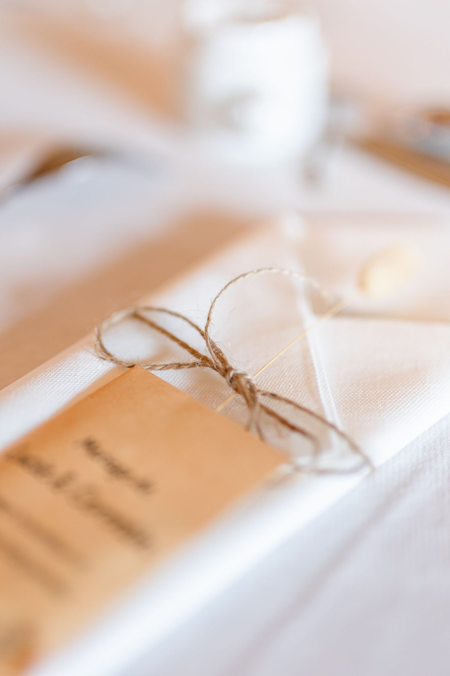 Close-up of name cards tied with twine string on white tablecloth.