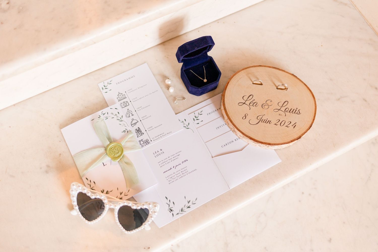 Wedding details and stationery arranged on a light surface with delicate floral designs.
