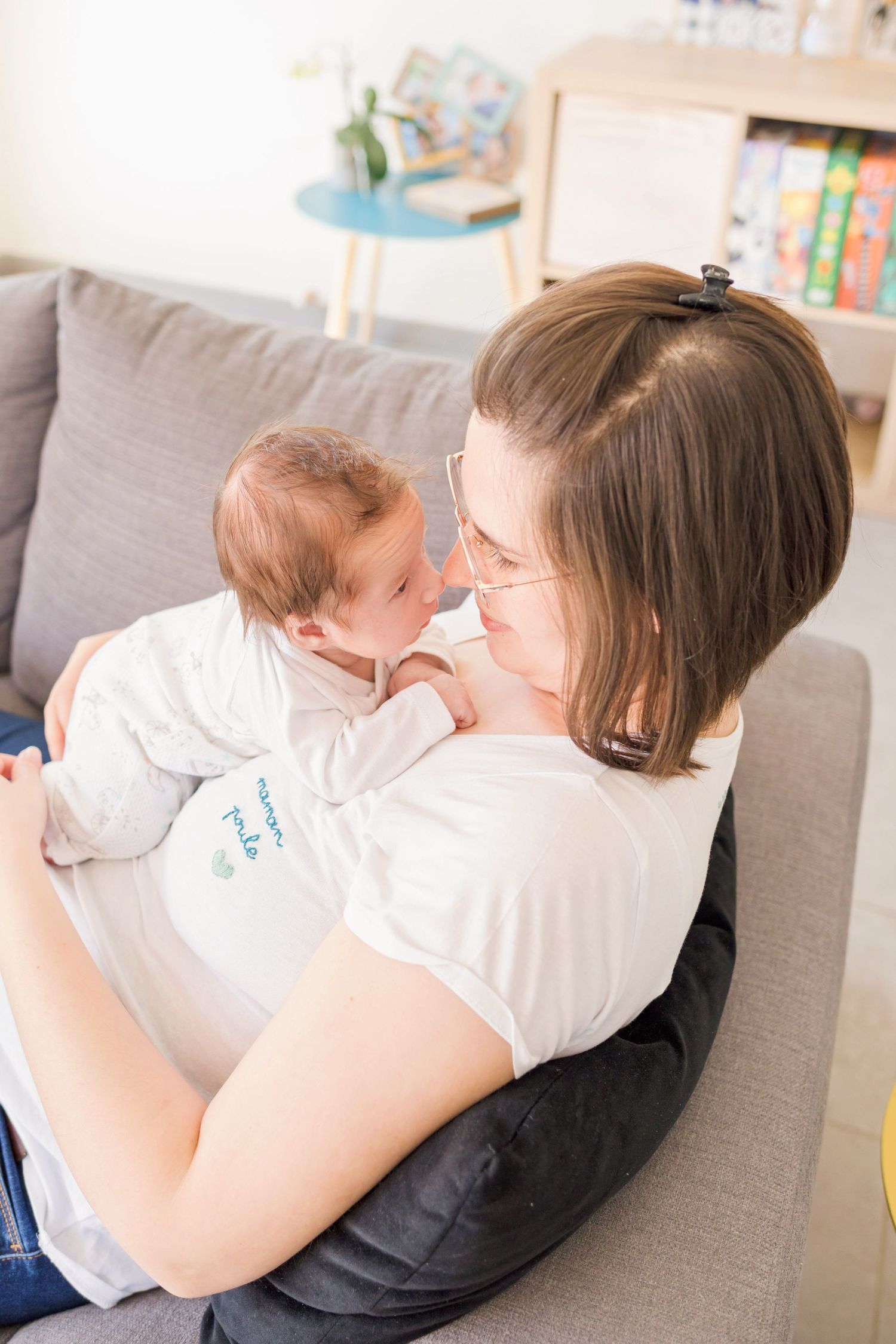 Tender bonding moment on grey couch in bright modern room.