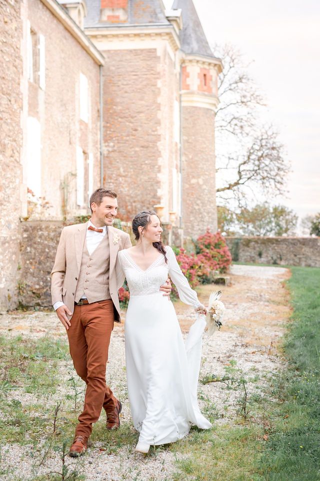 A romantic couple strolls together on grounds of a historic stone chateau in France.