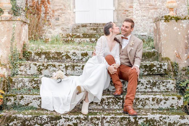 Couple seated on historic stone steps sharing a loving moment at French countryside manor.
