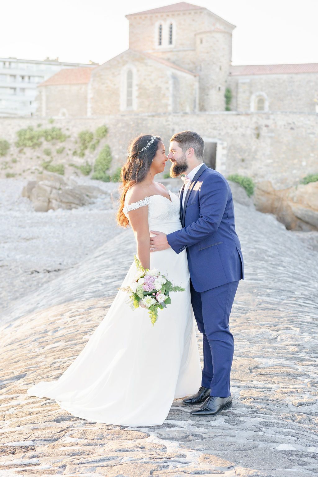 Romantic wedding portraits on ancient stone walkway by Mediterranean architecture.