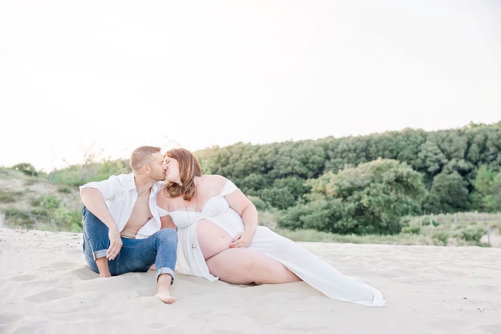 Intimate family maternity photo session on beach with couple in casual attire.