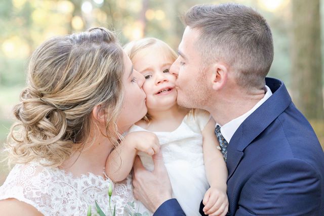 Sweet family moment captured during wedding photoshoot in wooded setting.