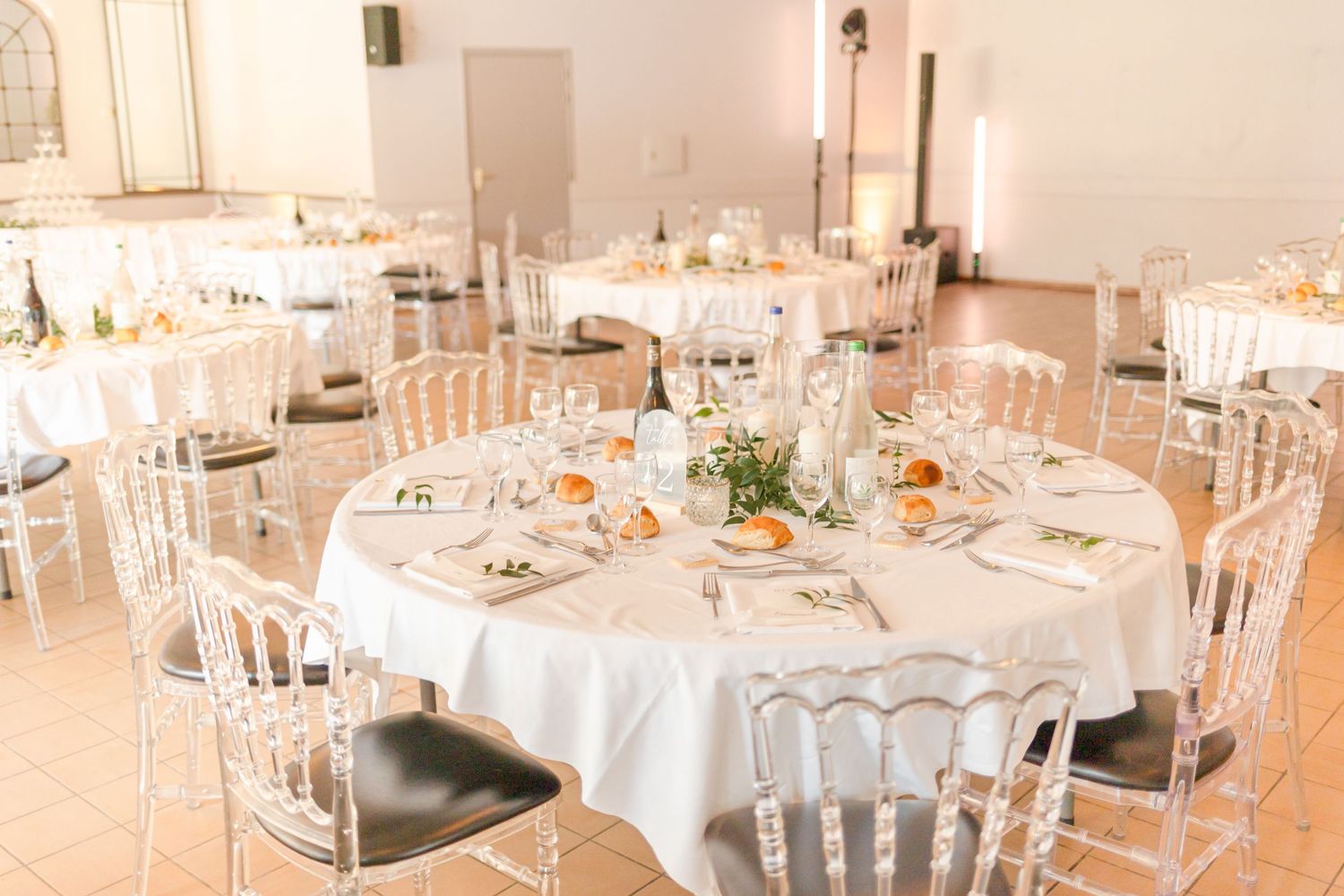Wedding reception hall set with round tables, white chairs and floral centerpieces.