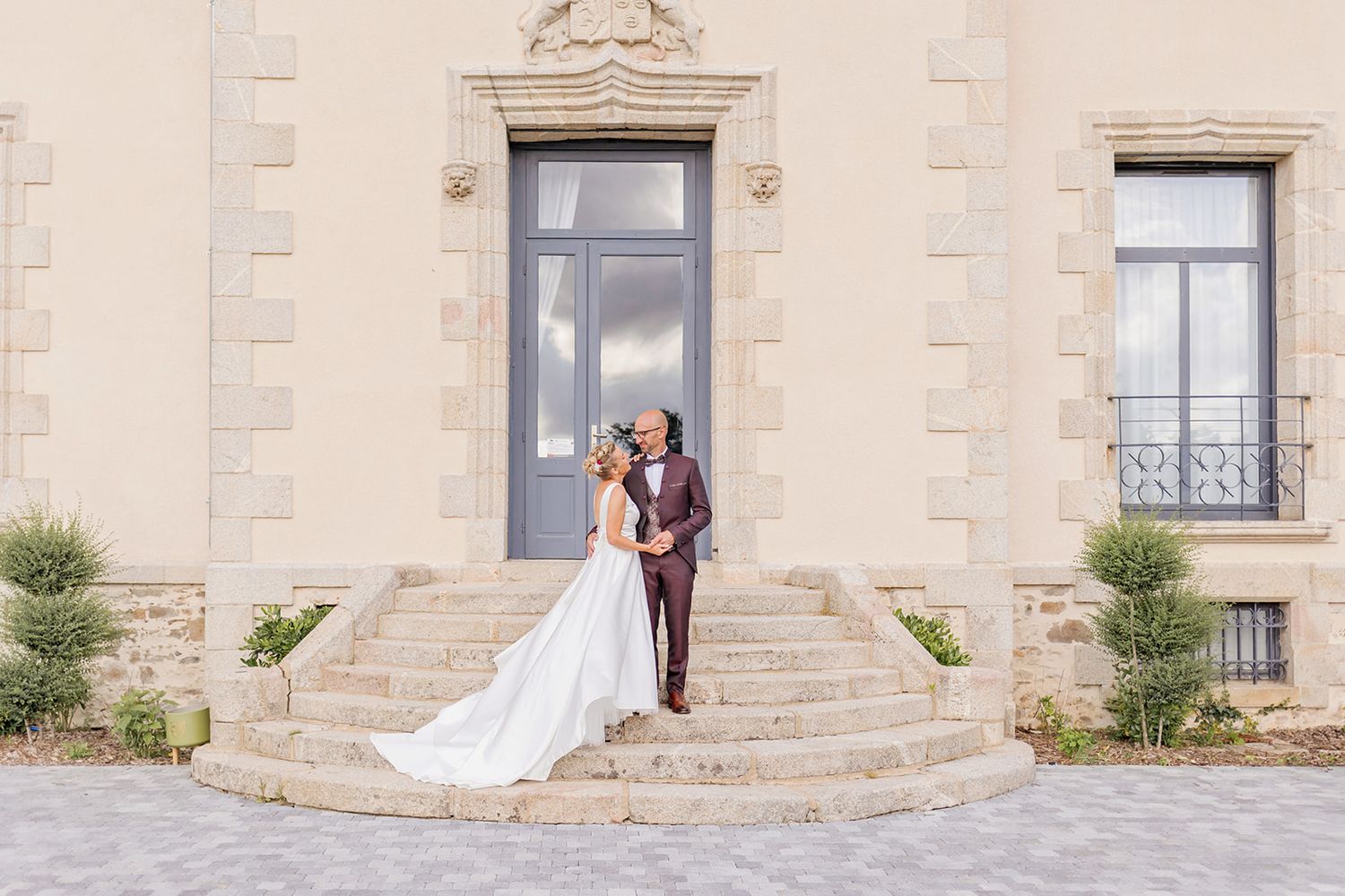 Elegant outdoor wedding ceremony setup with floral decorations on a lawn in front of a majestic French chateau.