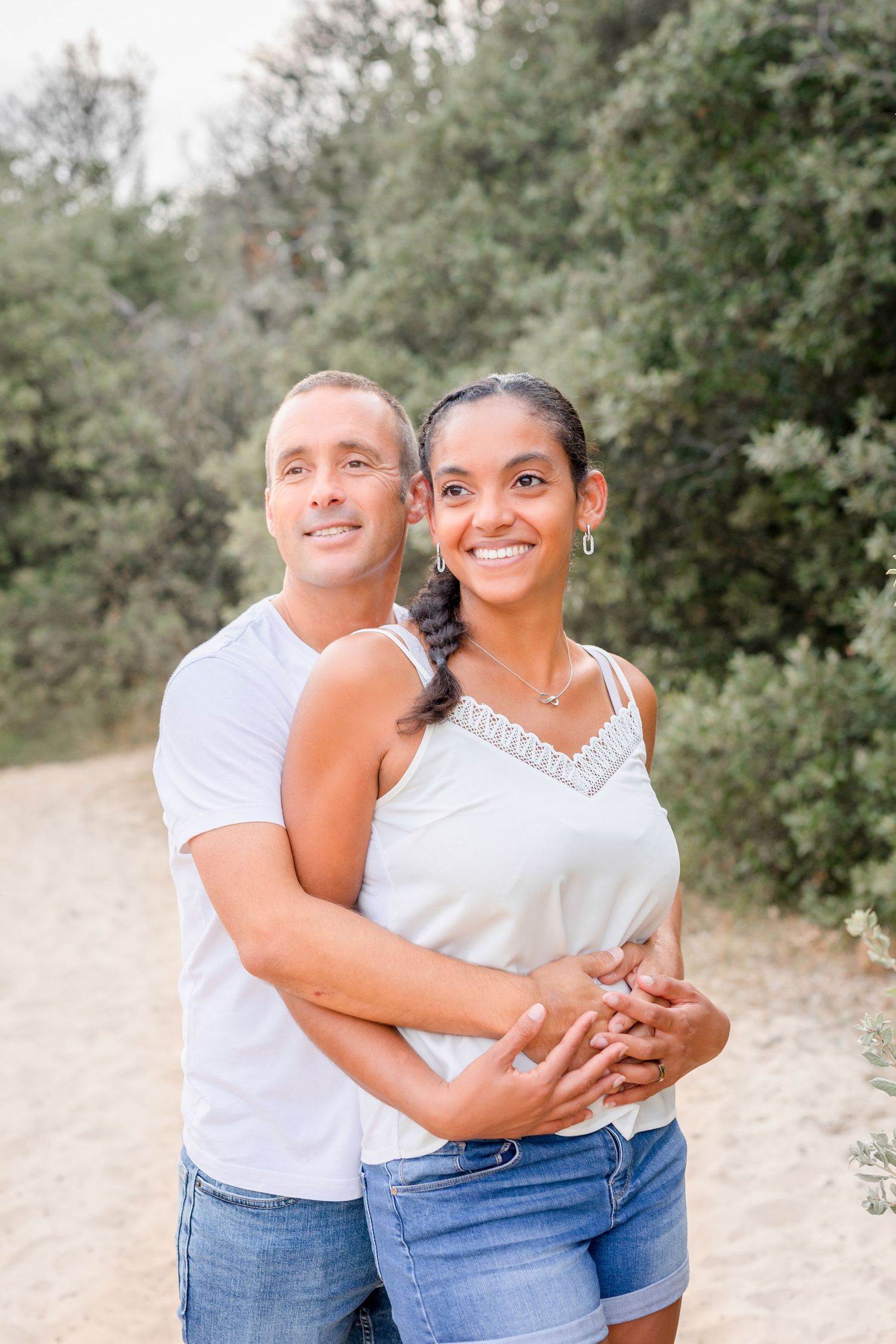 Happy couple sharing joyful moments during casual outdoor photo session in coordinated outfits.