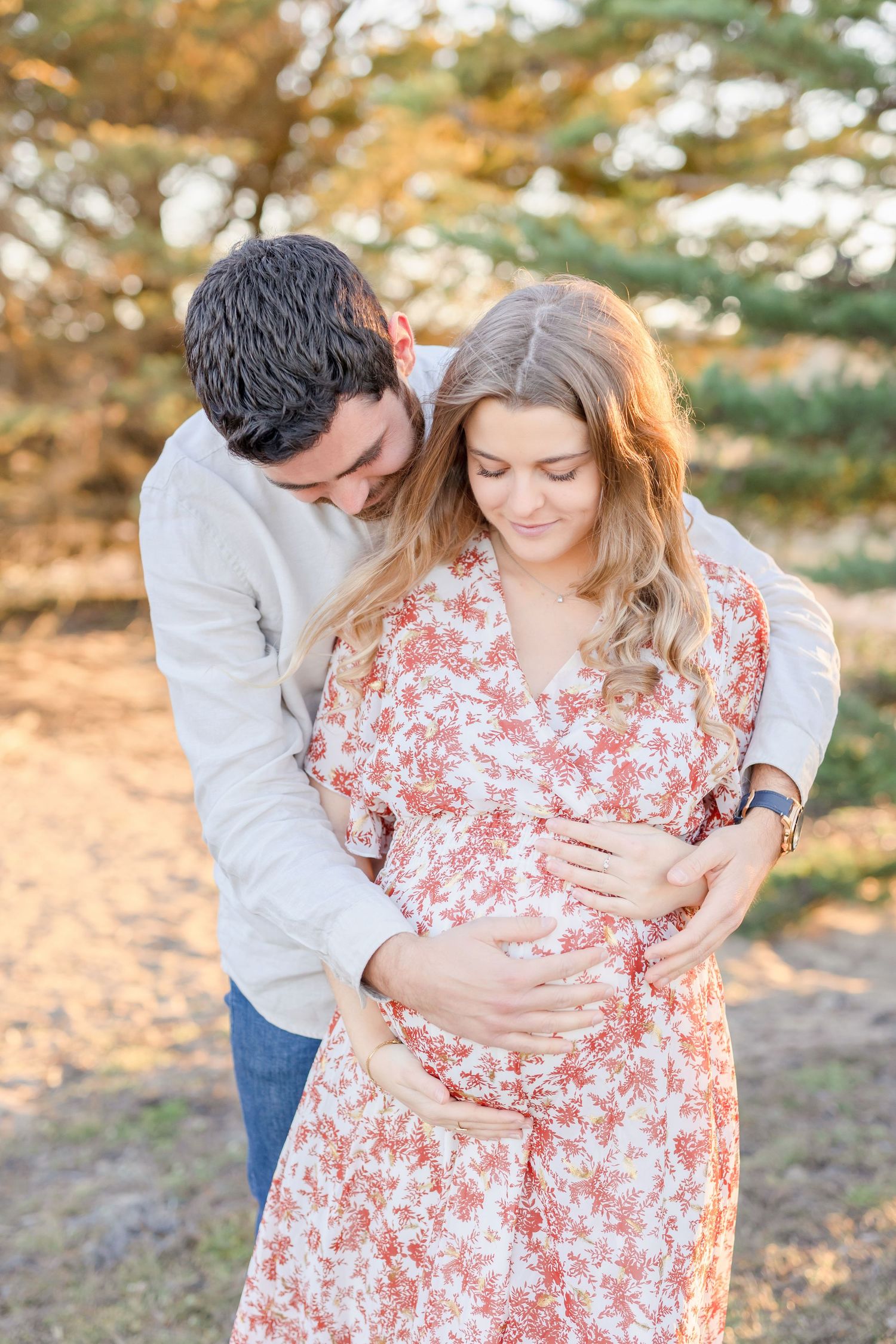 Tender maternity moment captured as couple embraces on a scenic path.