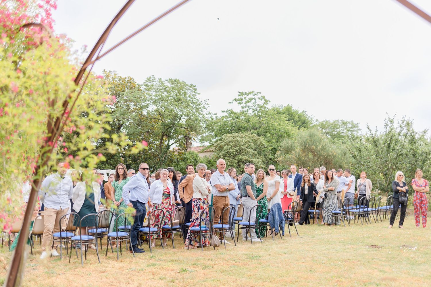 Wedding guests seated in rows of chairs at an outdoor garden ceremony.