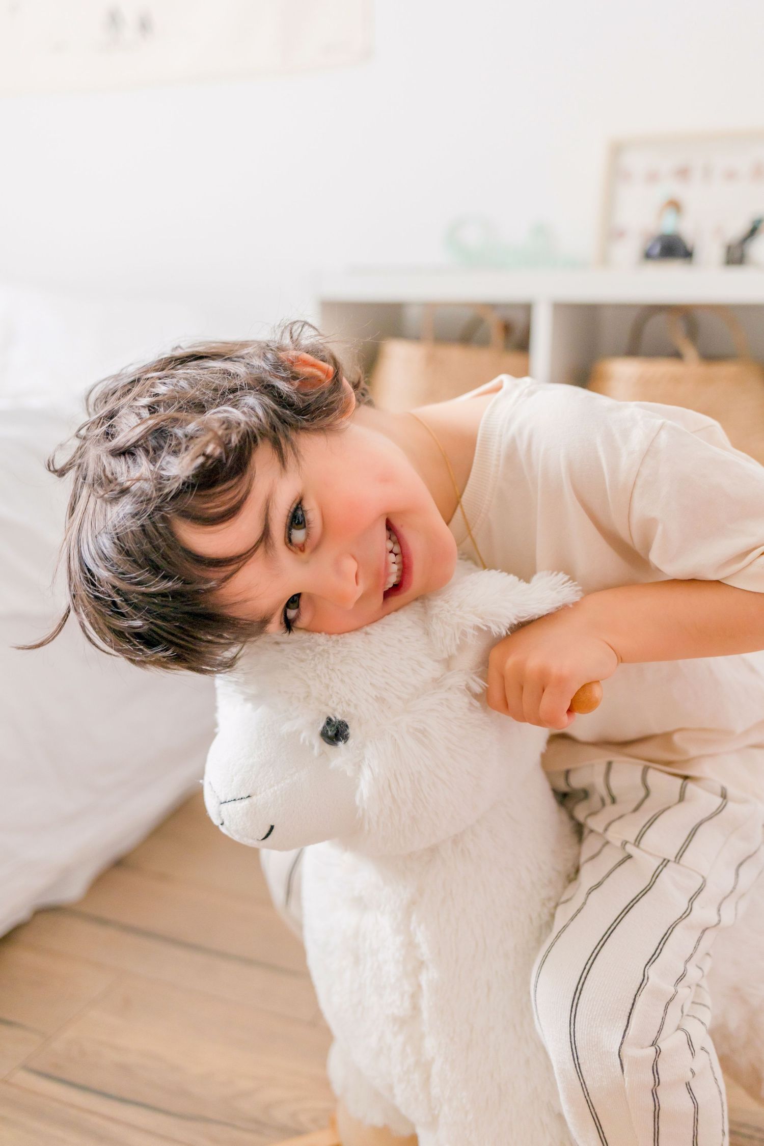 Child enjoying playtime with a plush rocking horse toy in a bright room.