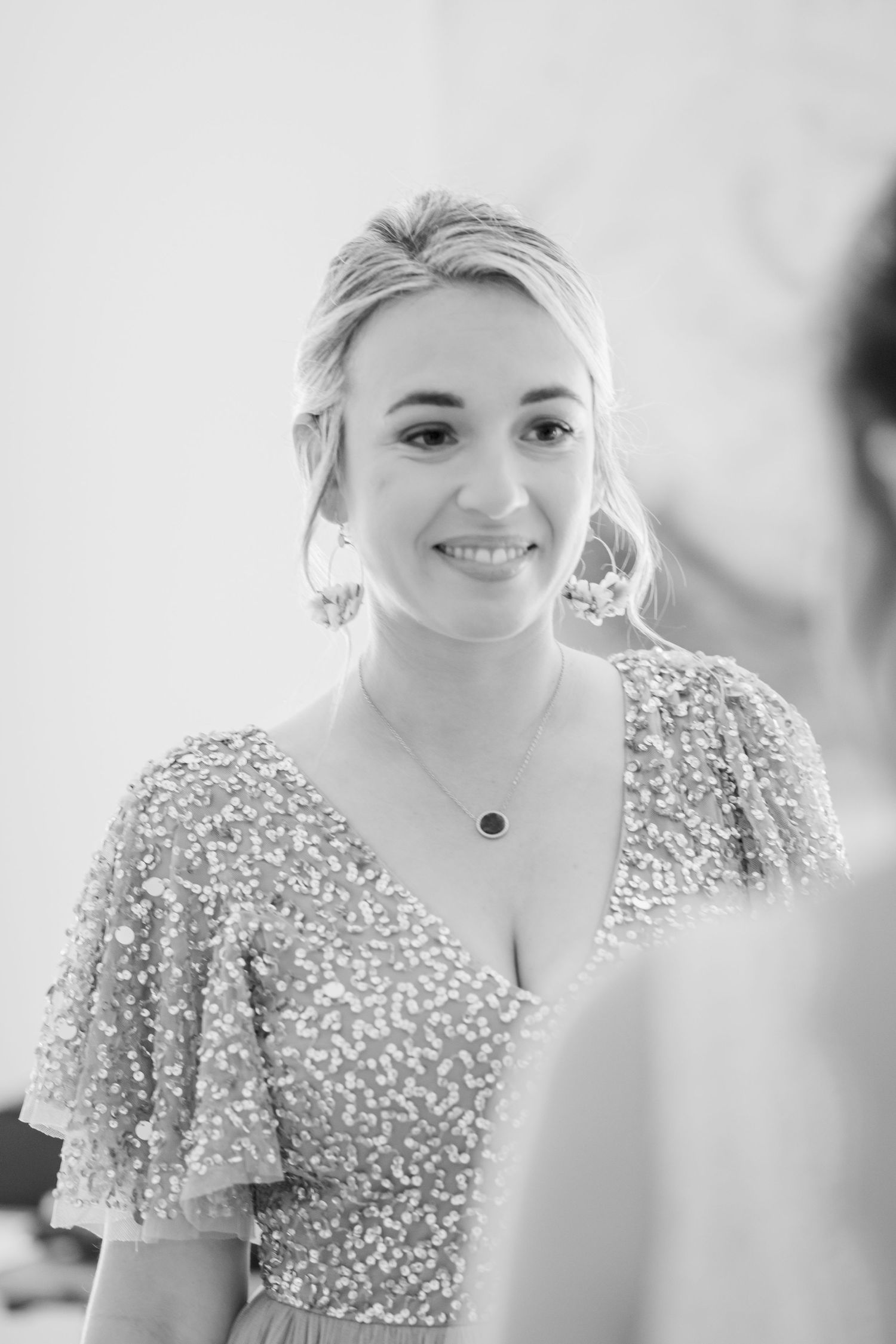 Bride in a sequined wedding gown with puff sleeves smiles during pre-wedding preparations.