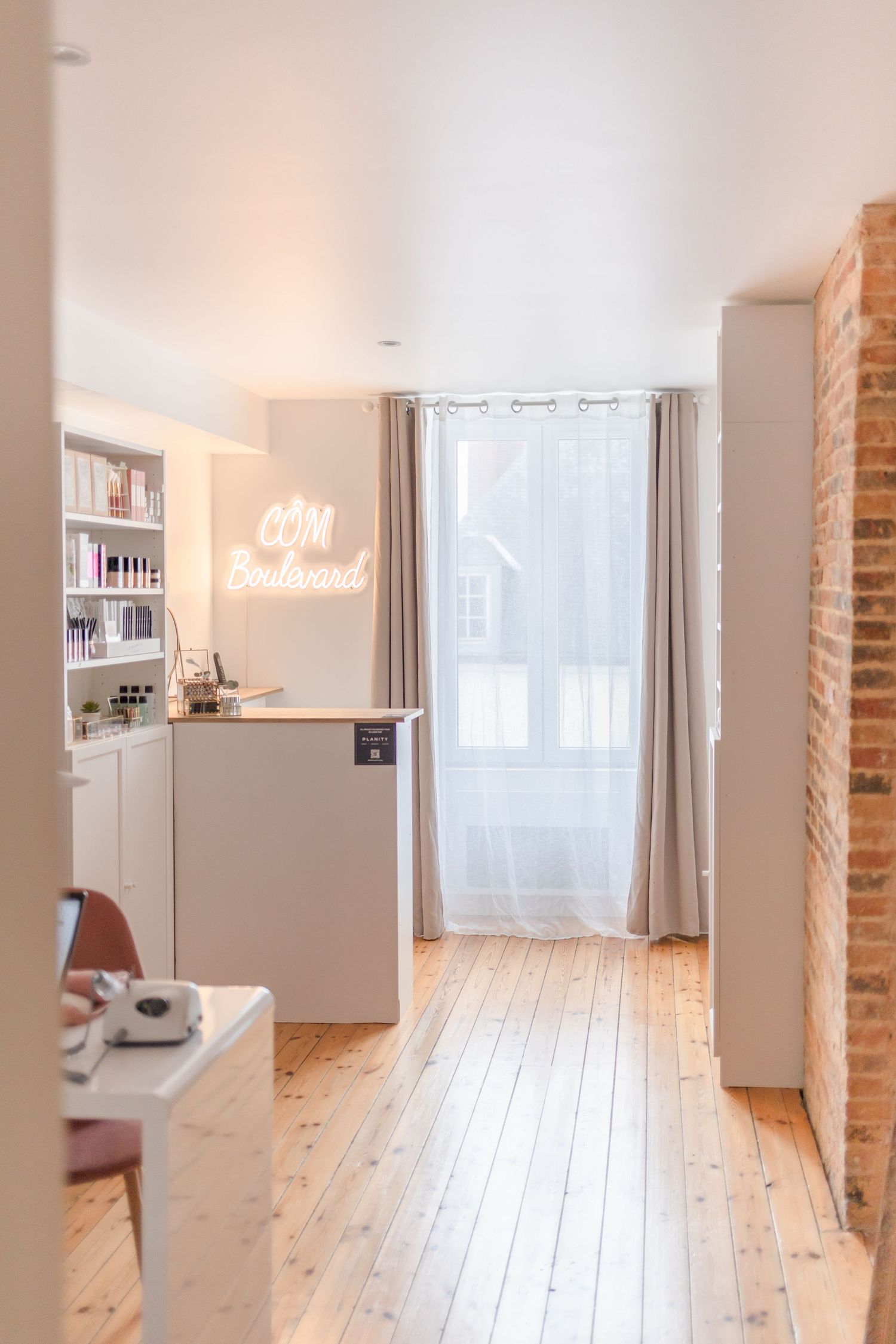 Modern interior hallway with wooden floors, white walls and glowing neon sign.