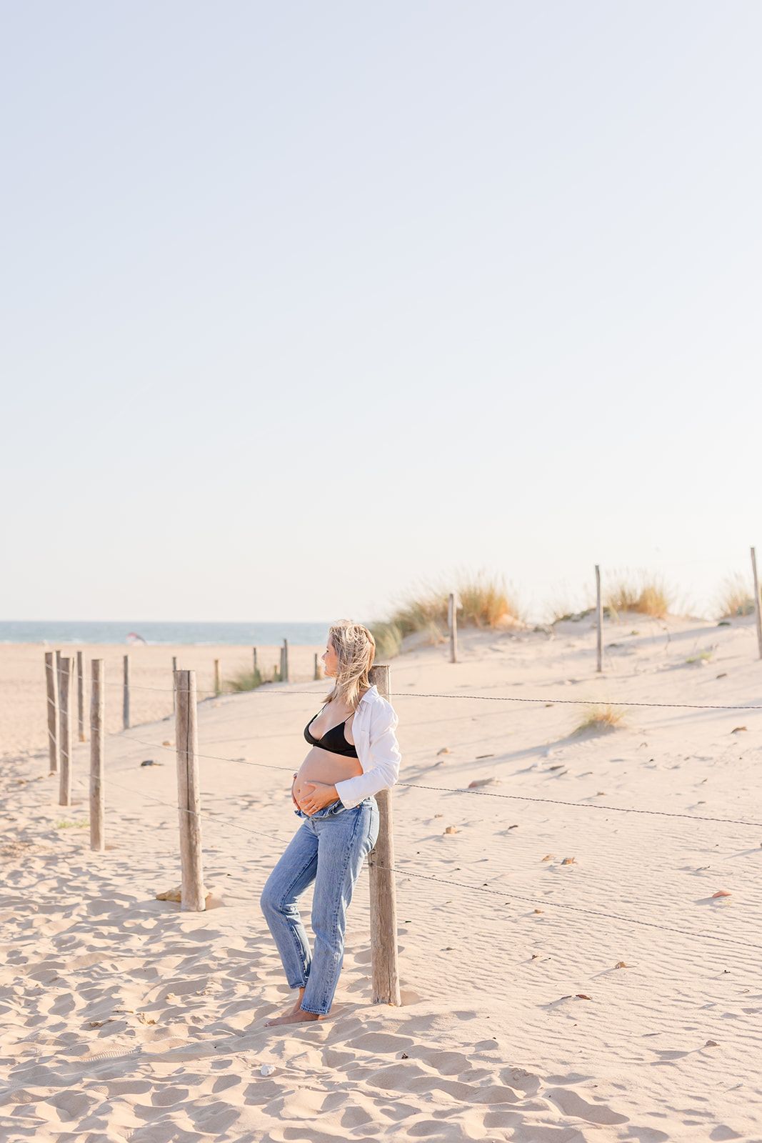 Three sequential photos show a person leaning playfully against wooden beach posts on a sandy shore at sunset.