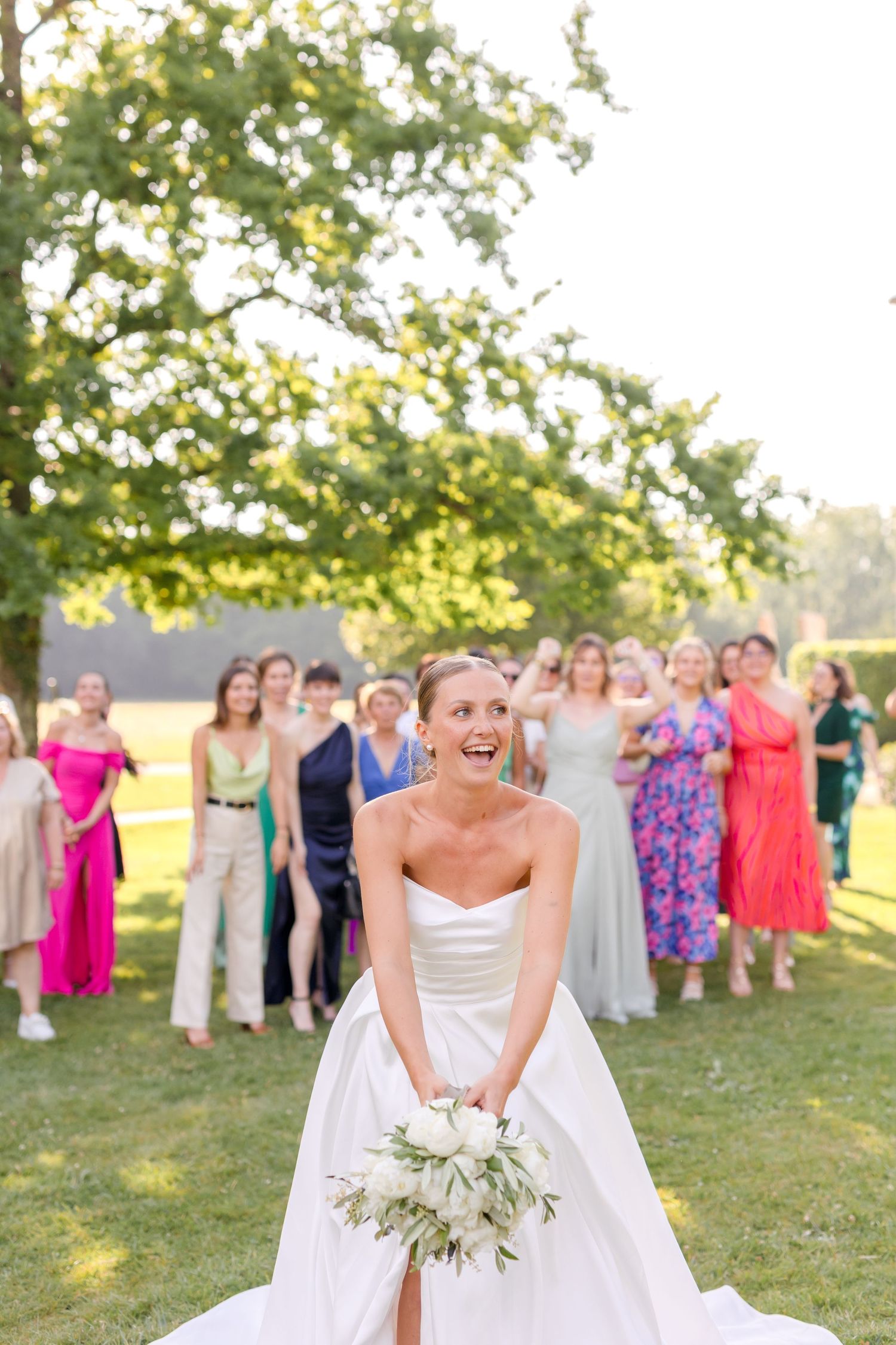 Wedding celebration with guest lineup outside chateau as bride poses with white bouquet.