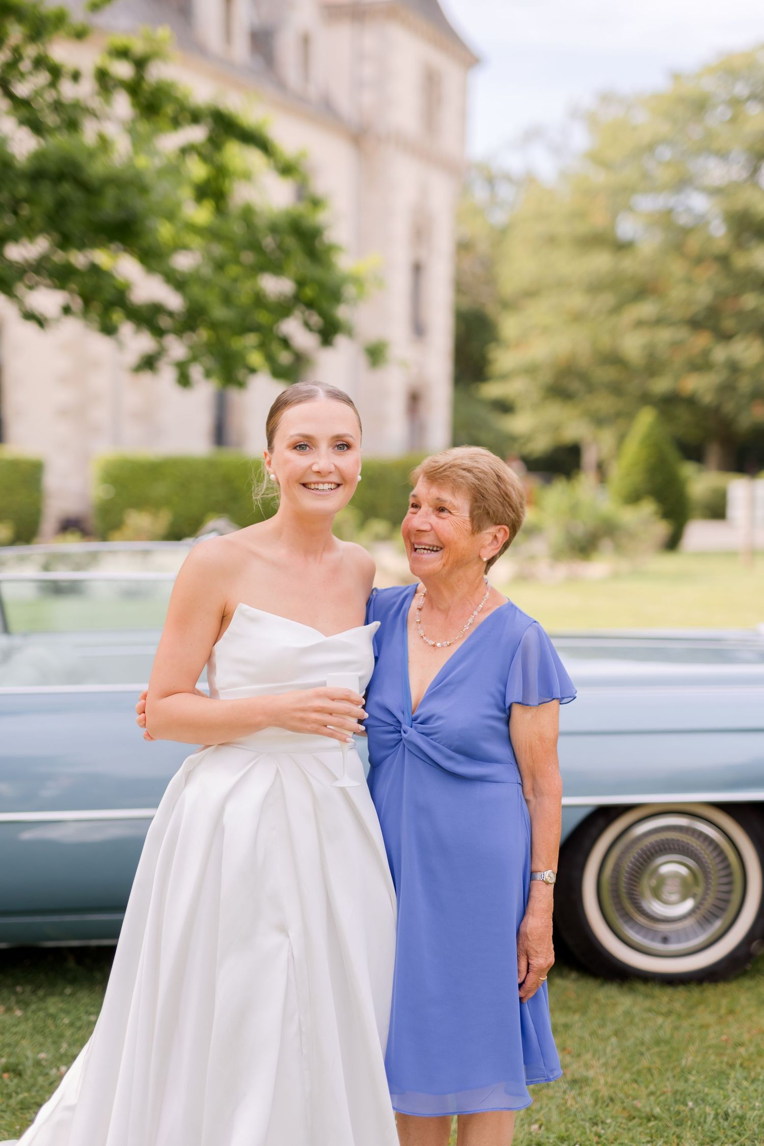 Wedding portraits with classic blue car backdrop show heartwarming interactions on a sunny day.