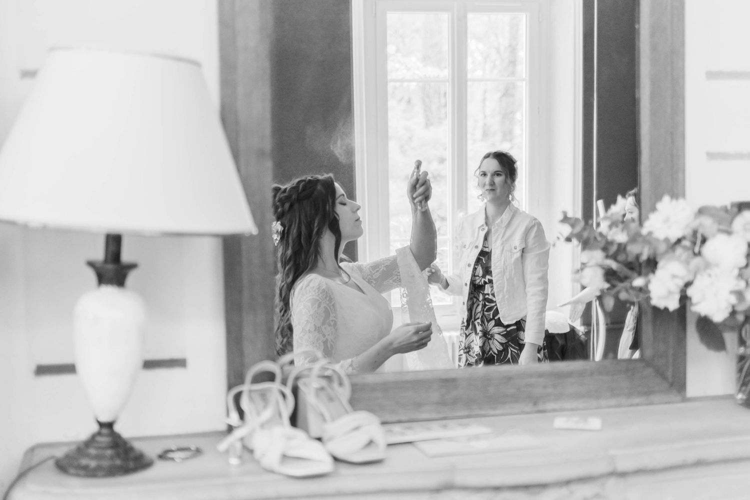 Black and white photo of wedding preparations with lamp and window in background.