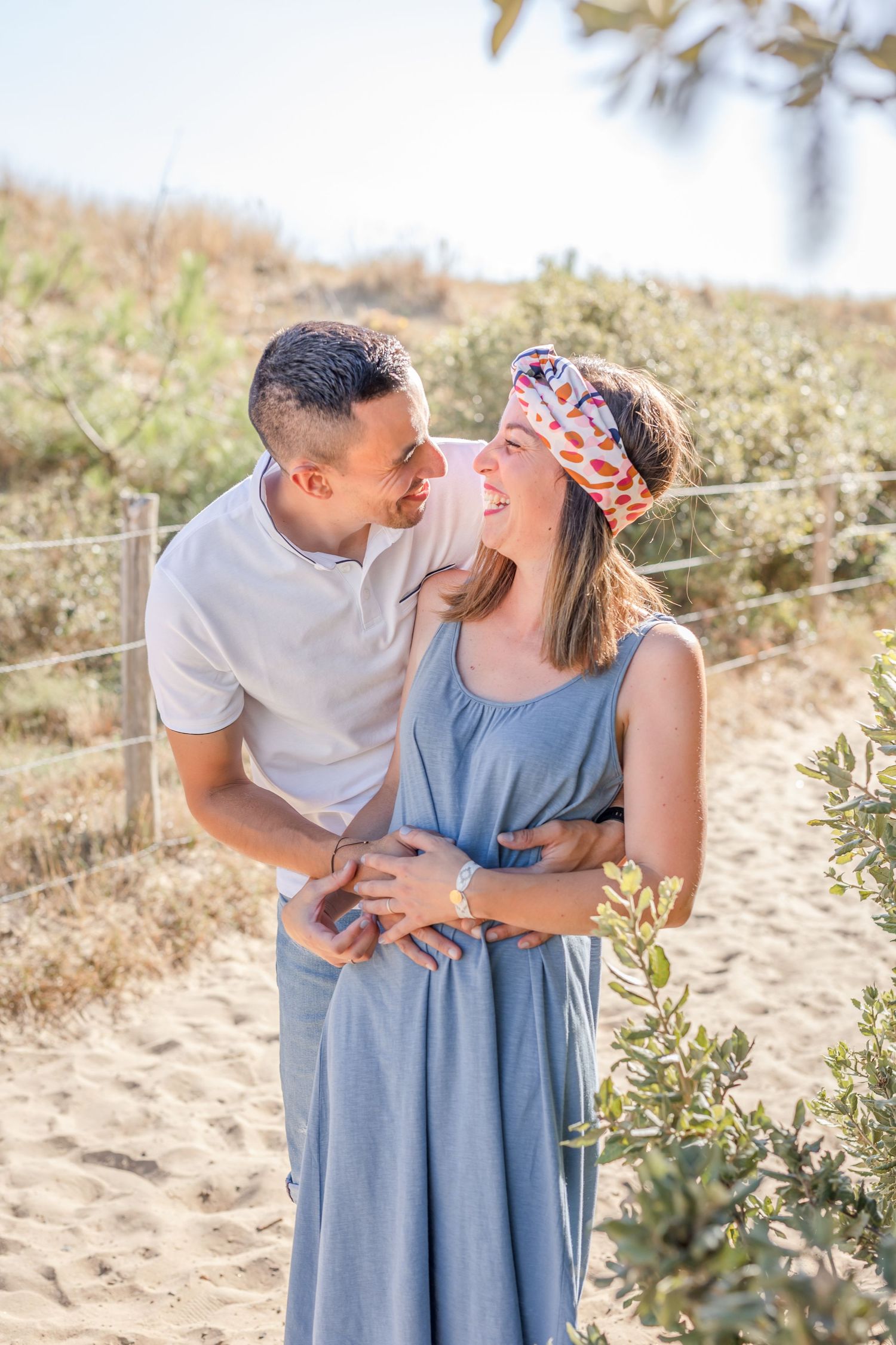 Intimate couple photos captured against coastal vegetation at sunset.