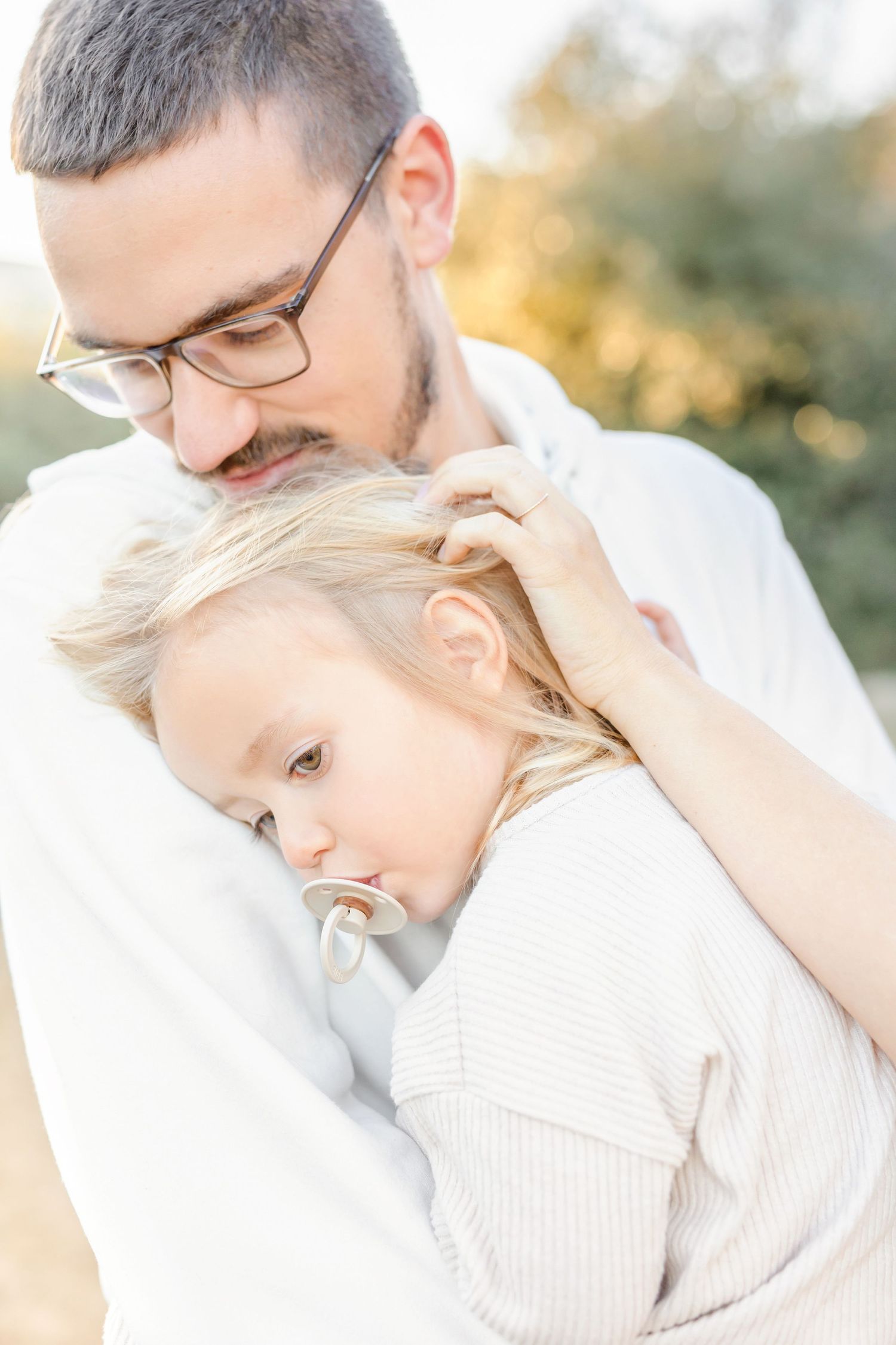 Close up portrait of parent and child in white sweaters sharing intimate moment outdoors.