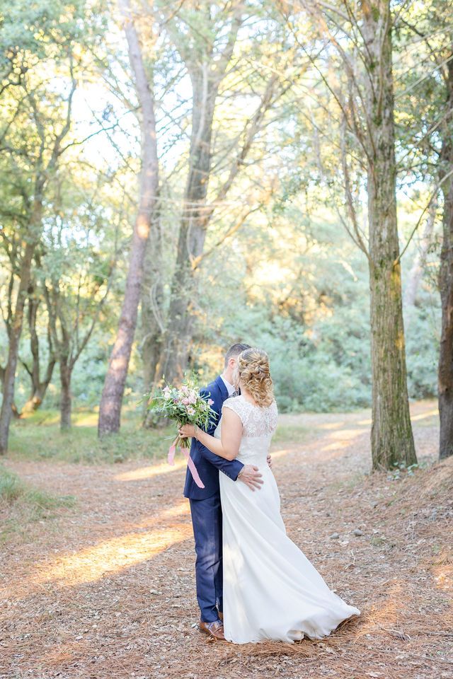 A romantic first look moment between a couple in formal wedding attire among tall forest trees.