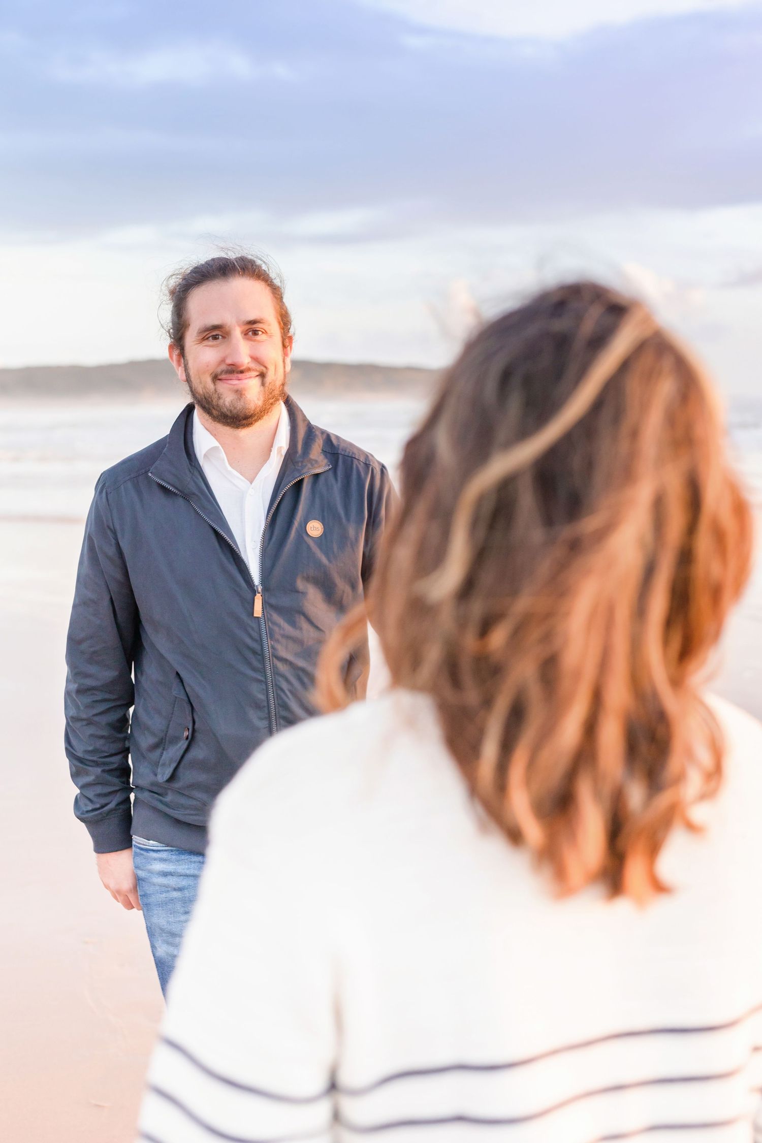 Candid engagement-style poses during beachside maternity photo session.