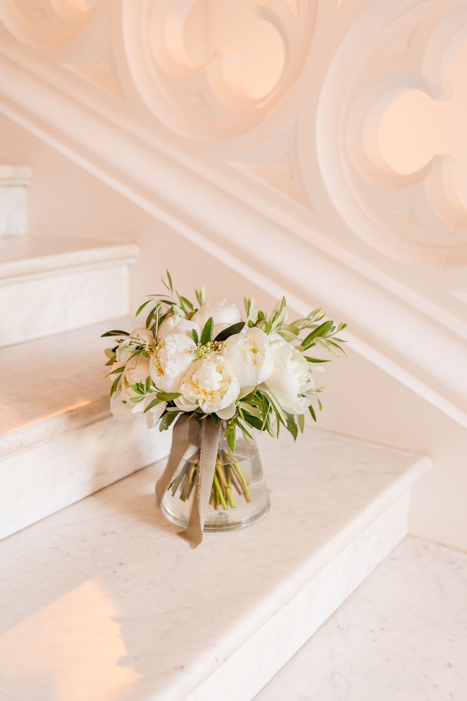 White floral arrangements in small glass vases on a neutral surface with soft lighting.