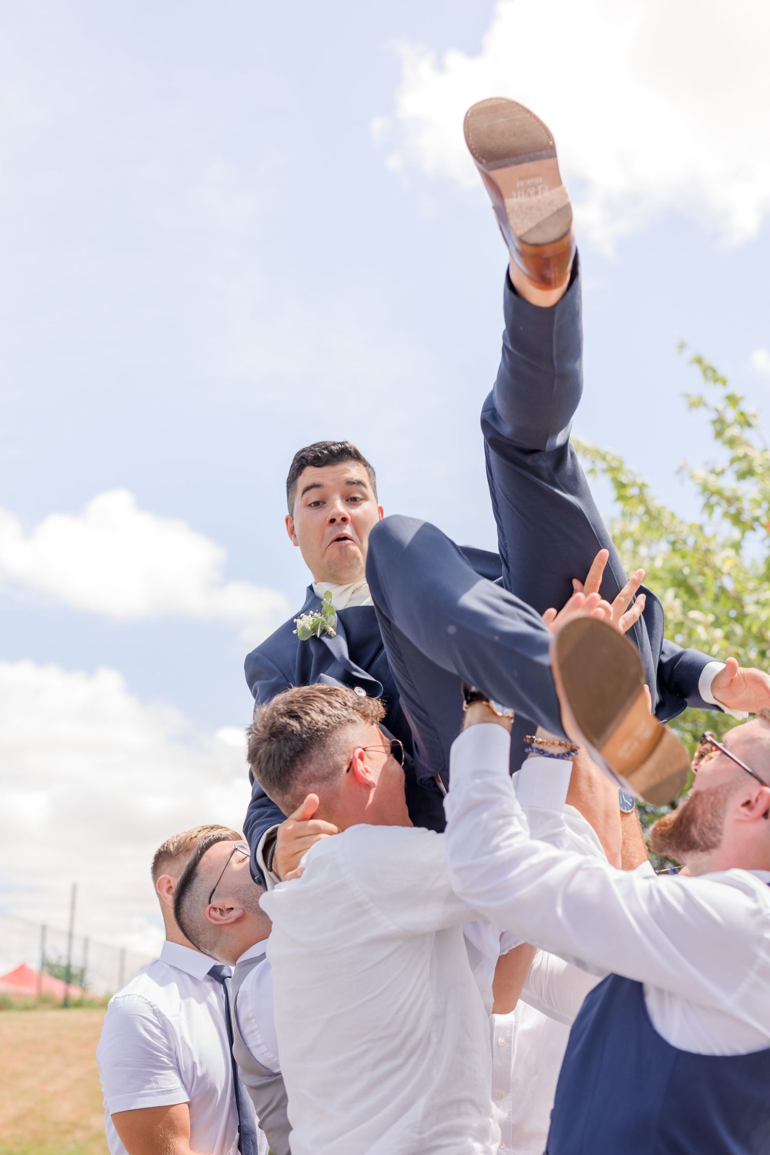 Groomsmen lifting someone up during outdoor wedding photo session.