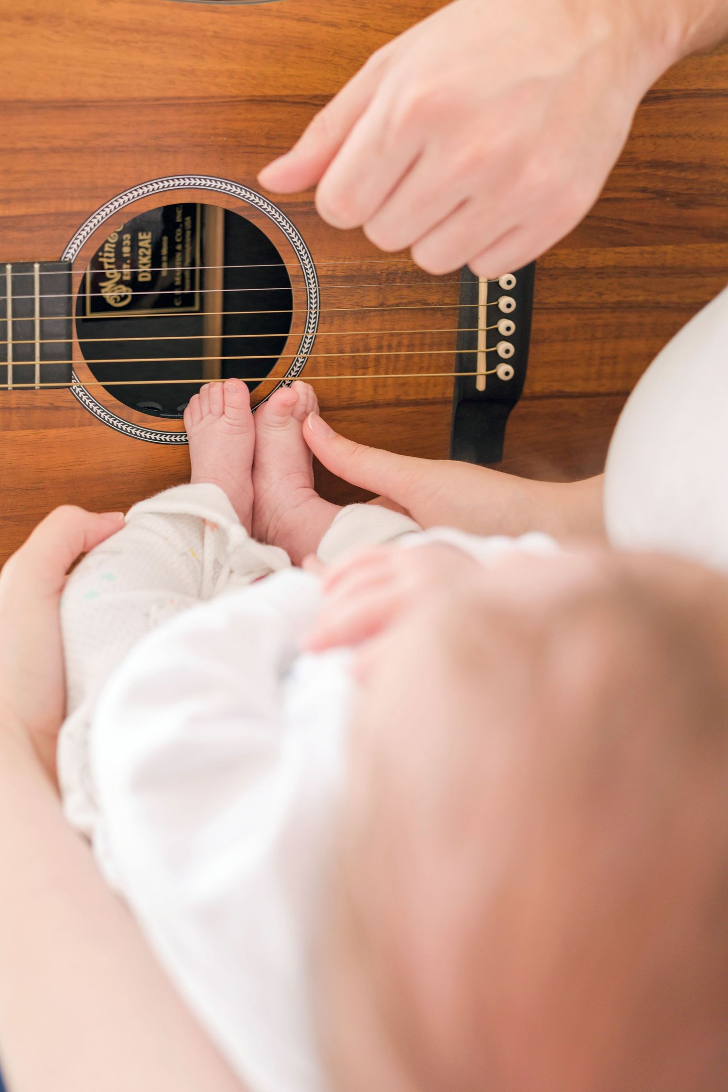 Close-up view of hands playing a wooden ukulele with intricate details visible on the instrument.