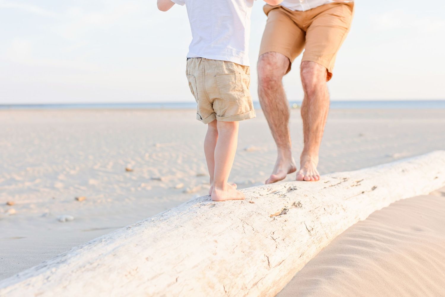 Bare feet walking along a sandy beach ridge during golden hour.