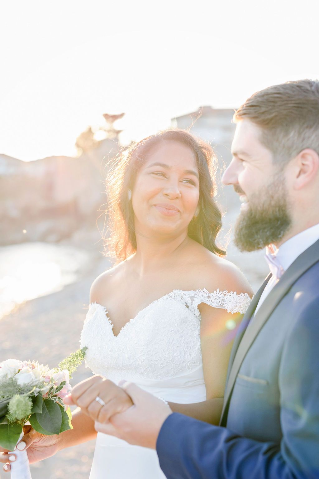 Romantic sunset wedding couple sharing loving moments with gentle sunflares in the background.