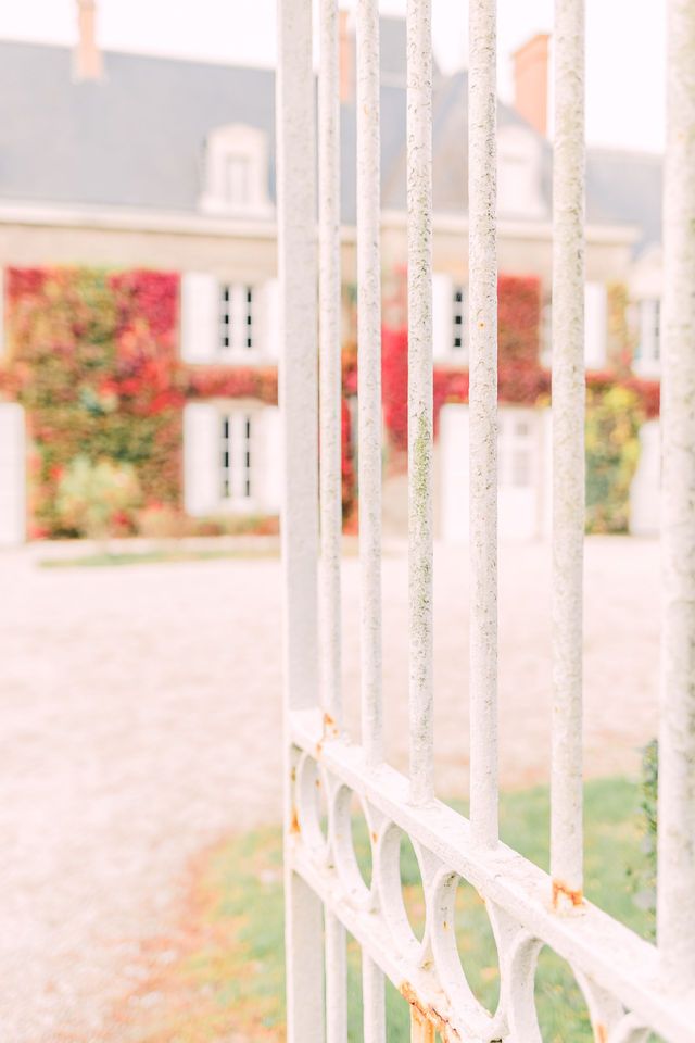 White picket fence detail with soft focus background of historic estate building.