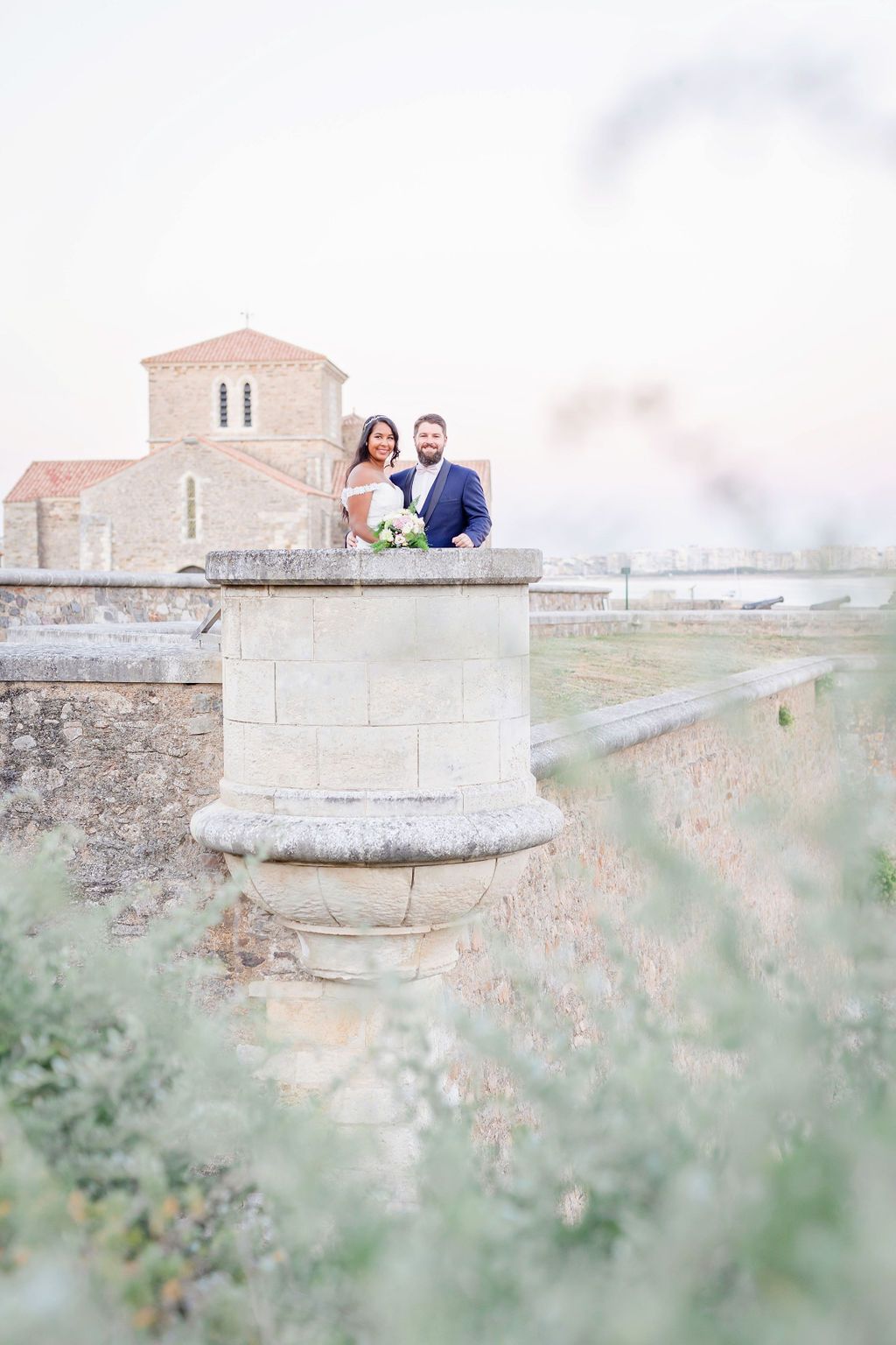 A couple enjoying sunset views from a historic stone fortress wall near a church.