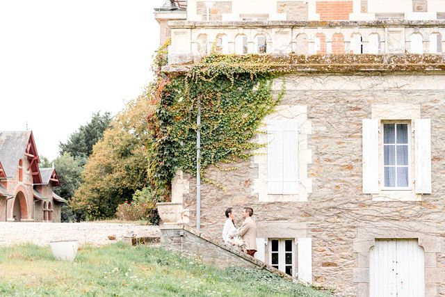 Stone chateau with ivy-covered walls and white shuttered windows in French countryside.
