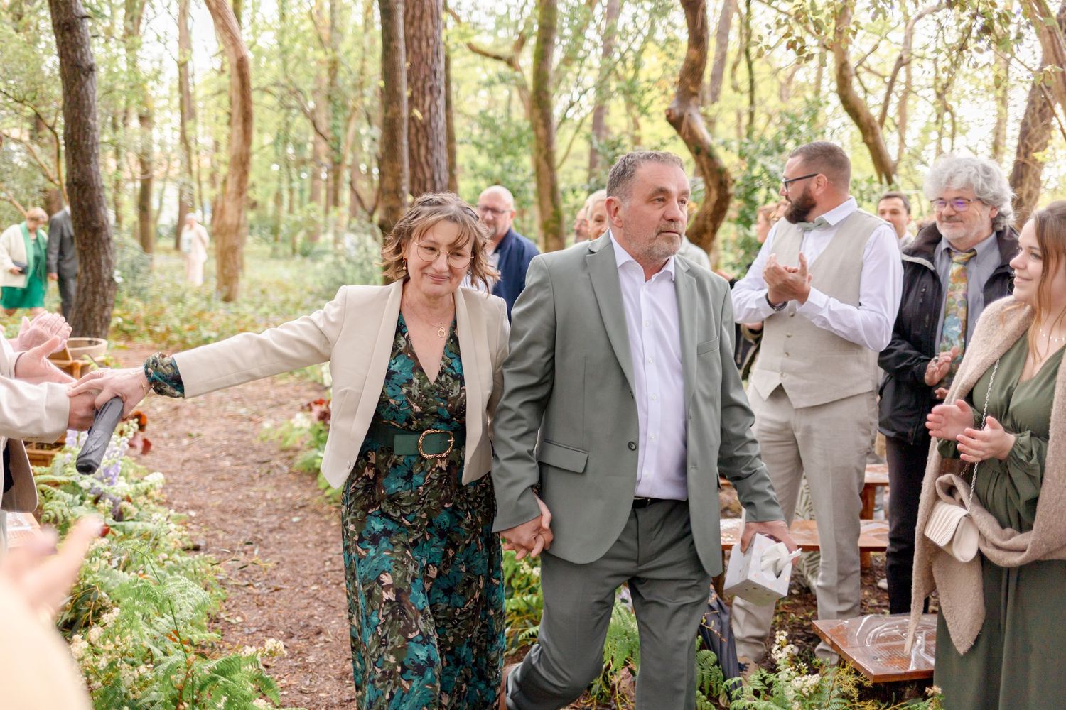 Wedding guests walking along a woodland path during an outdoor ceremony.