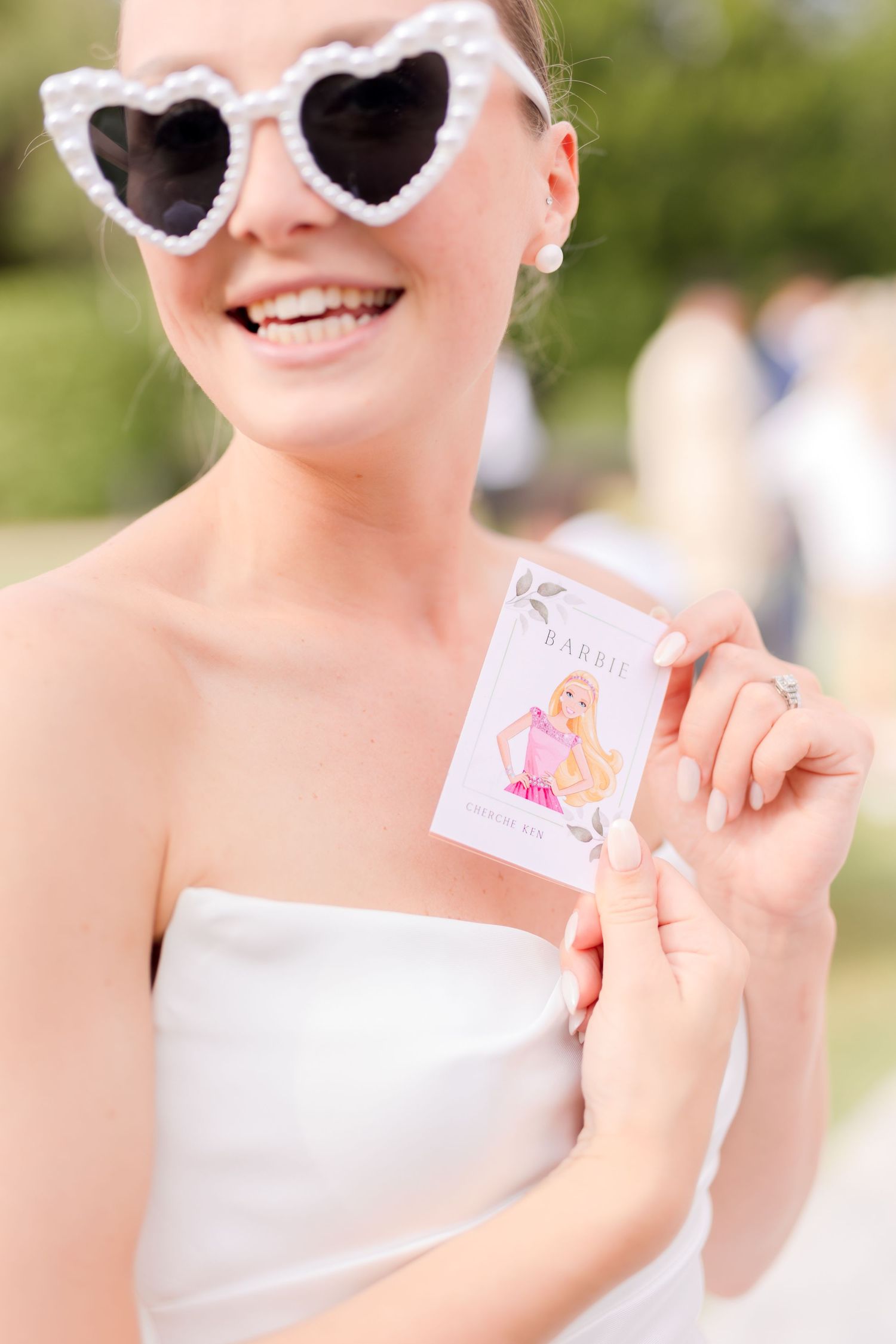 Bride wearing stylish white sunglasses smiles radiantly during outdoor summer wedding.