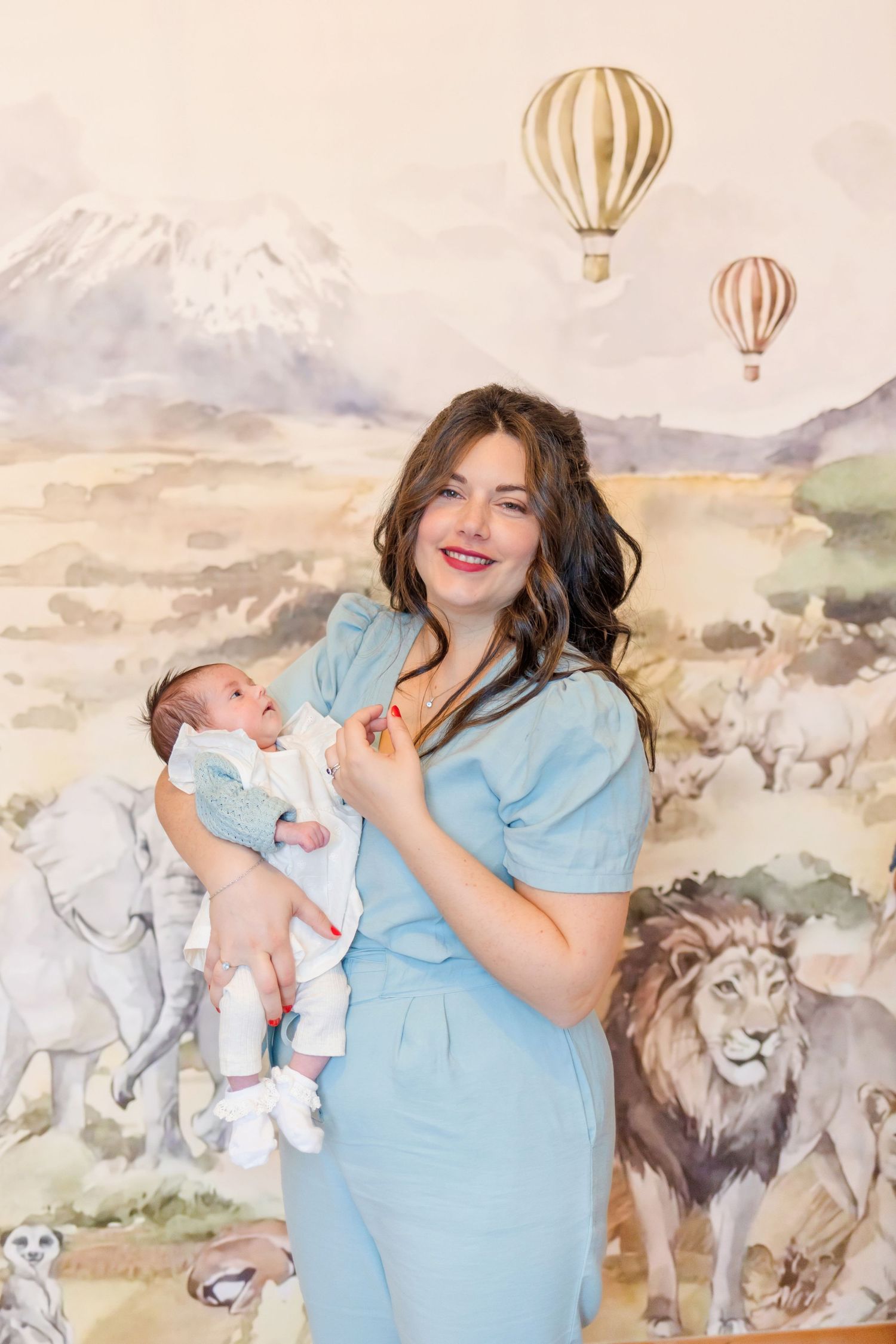 A joyful moment captured against a safari-themed nursery wall with hot air balloons and lions.