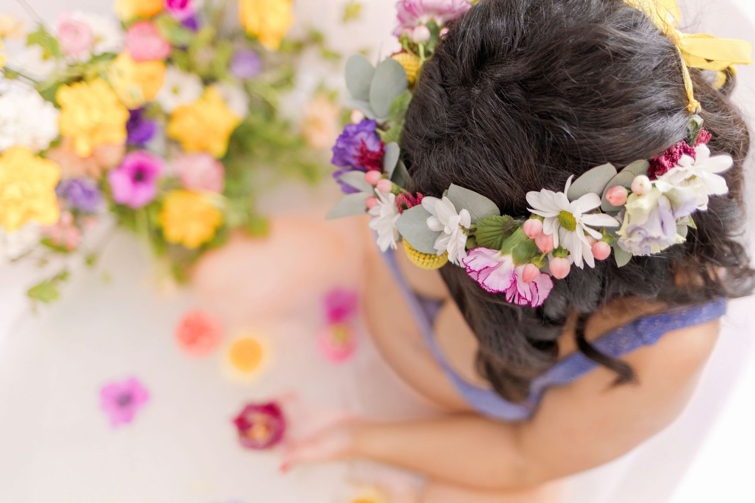 Overhead view of a floral-themed bath setup with scattered petals and flower crown.