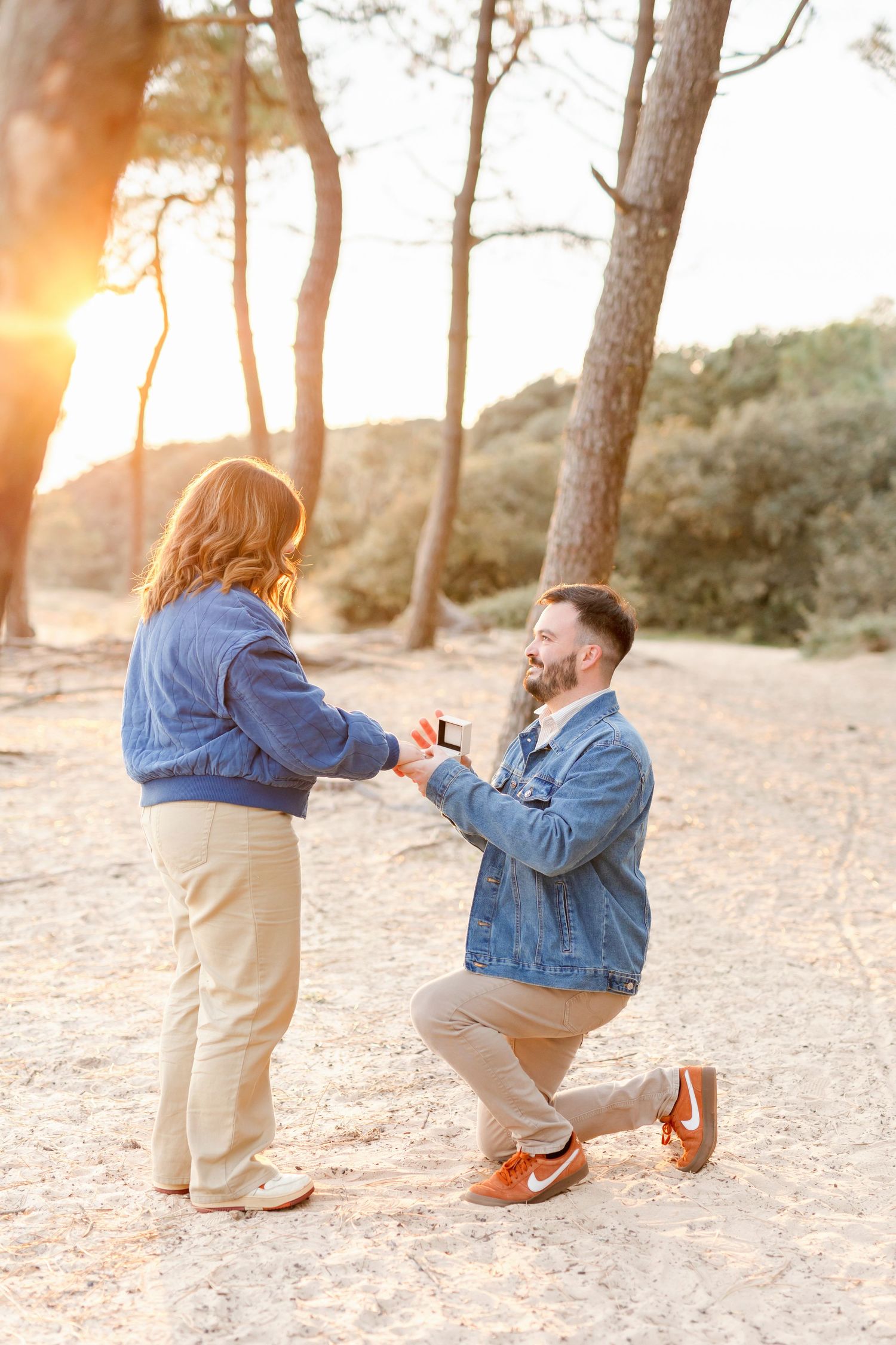 Sweet proposal moment captured at sunset on beach with couple in casual attire.