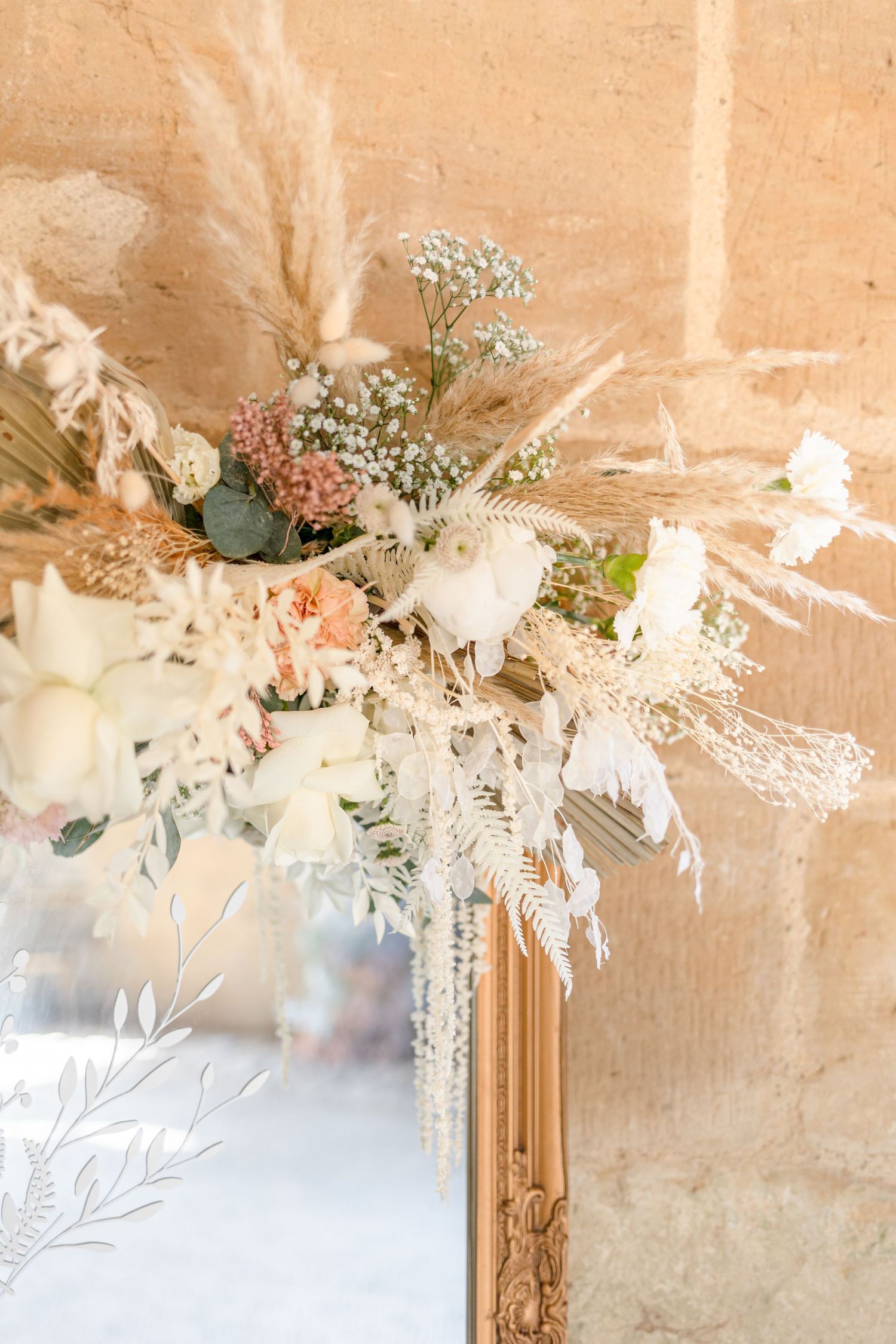 Delicate floral arrangements with white flowers and foliage hang from a stone ceiling creating an elegant ambiance.