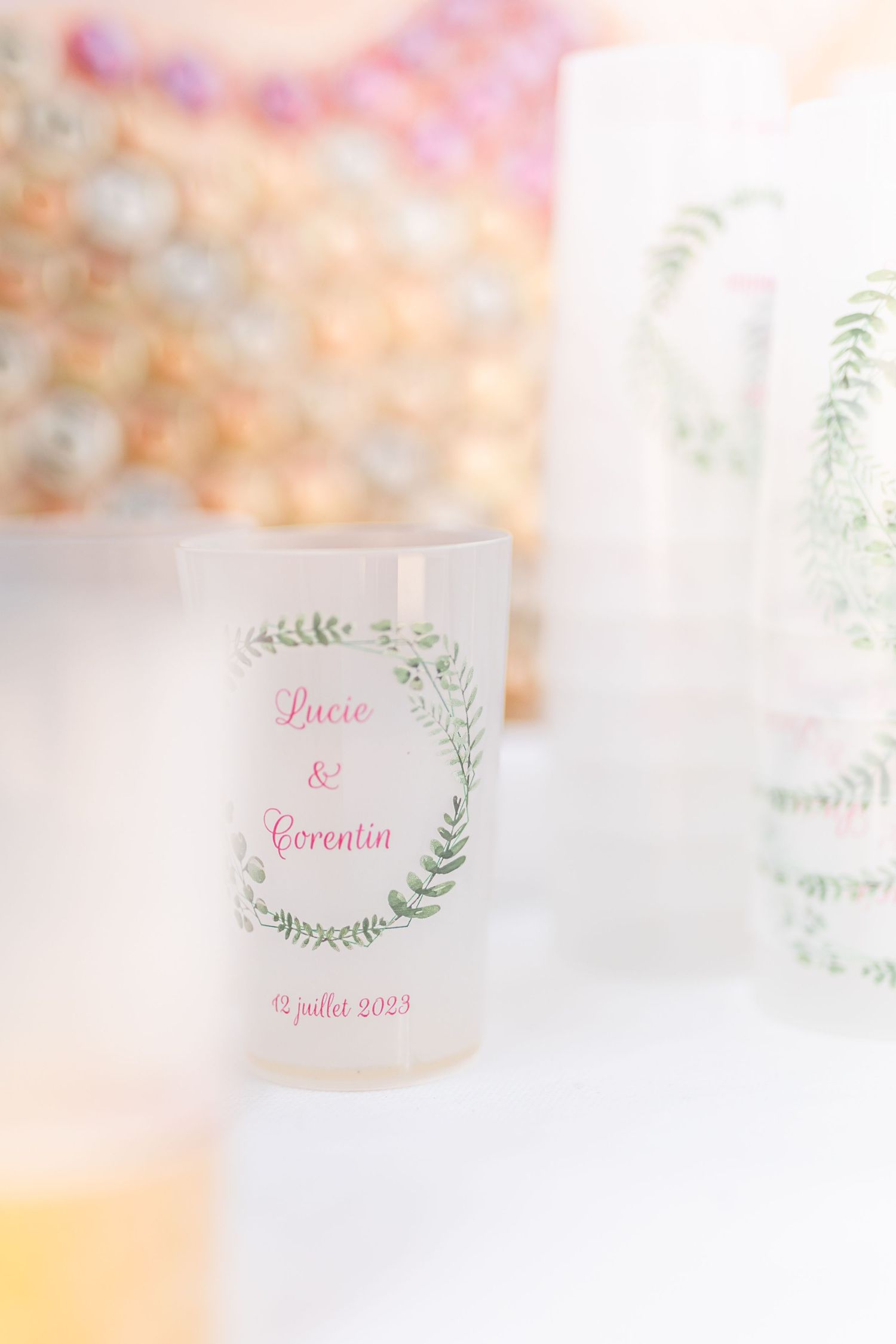 Wedding favor candles with delicate green leaf designs and pink text.