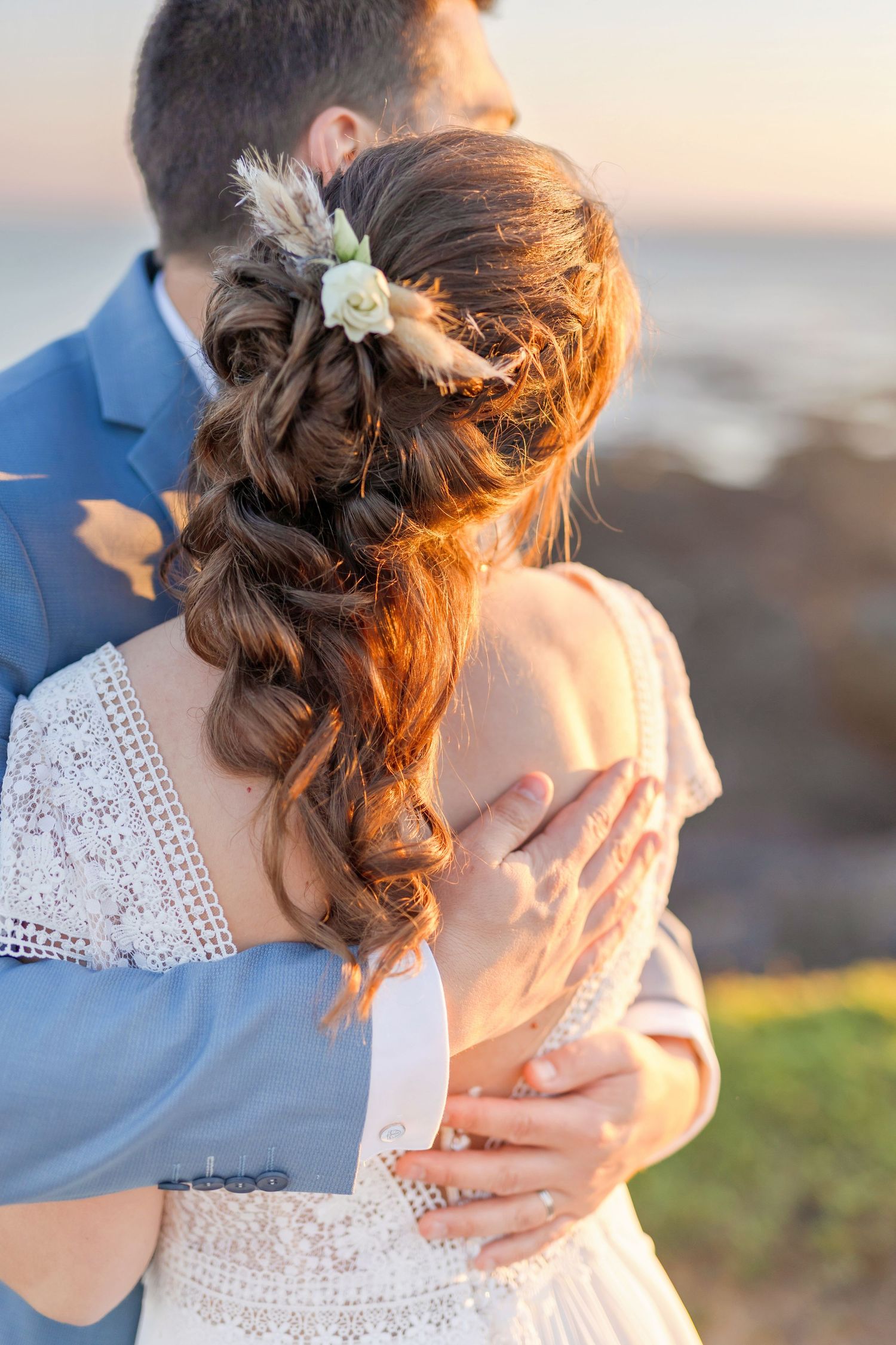 Elegant bridal updo with floral accent photographed during golden hour.