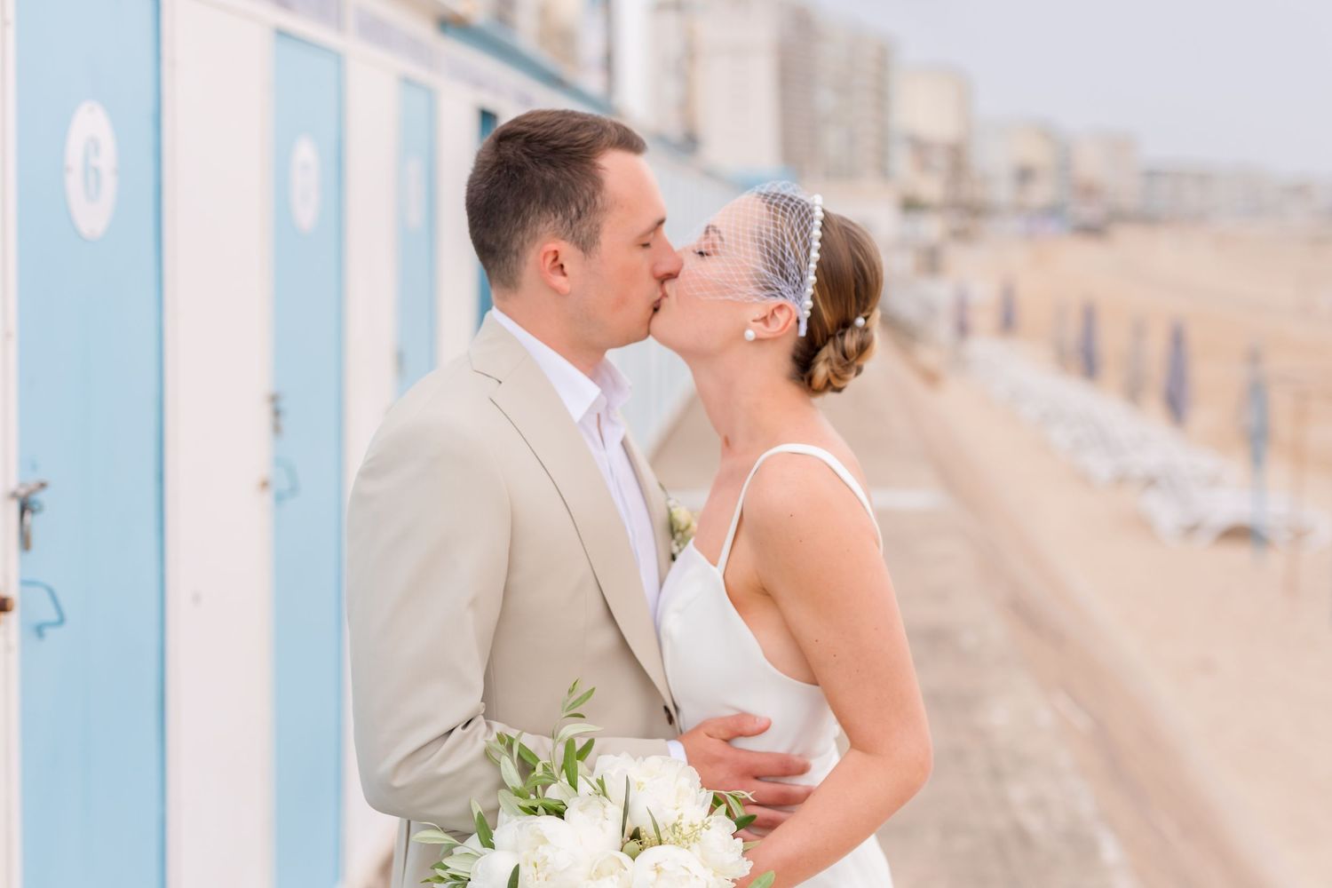 A romantic seaside wedding moment captured against coastal architecture.
