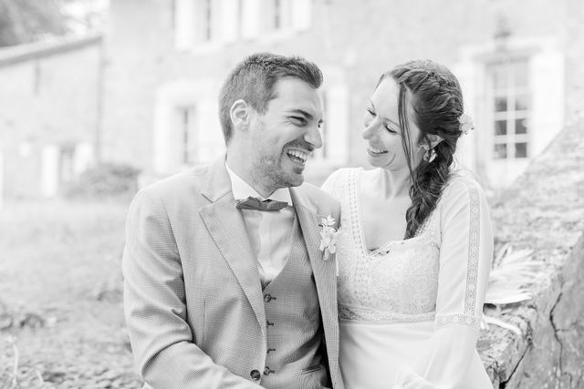 Black and white candid moment of couple sitting together by historic building.
