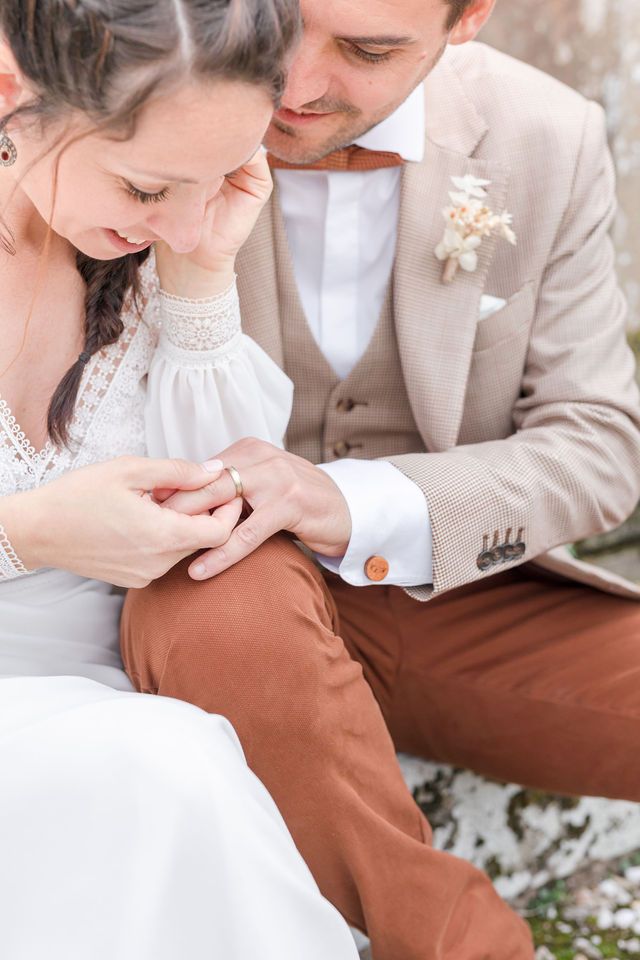 Close-up of wedding attire details showing lace dress and beige suit.