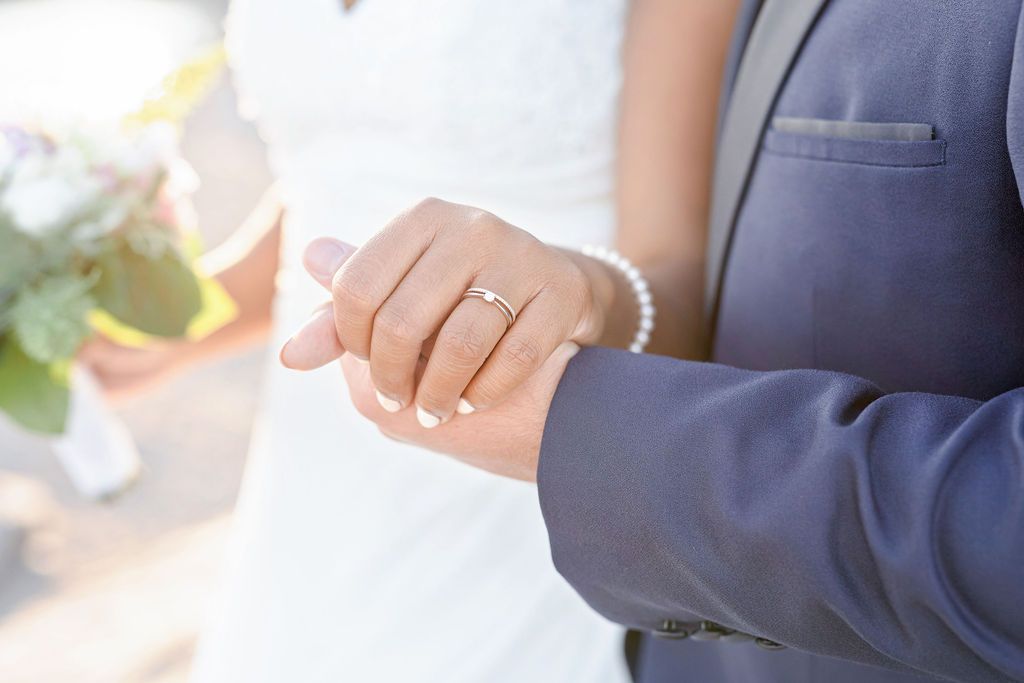 Close up of couple's hands showing wedding ring details during romantic sunset photoshoot.