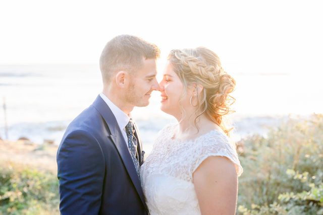 Intimate wedding portrait with sunlit coastal backdrop.